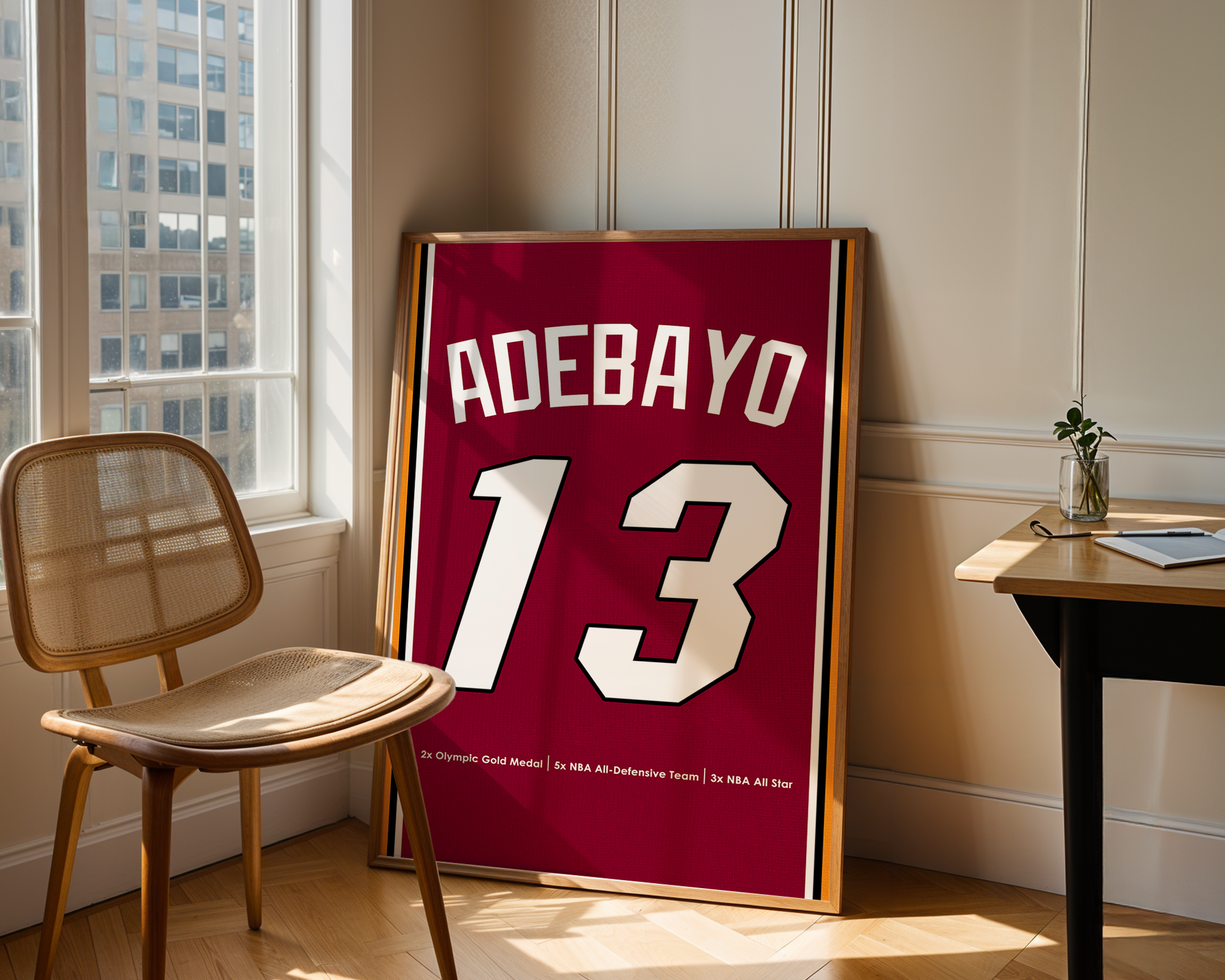Framed sports jersey with 'Adebayo 13' in a room with a window and chair.