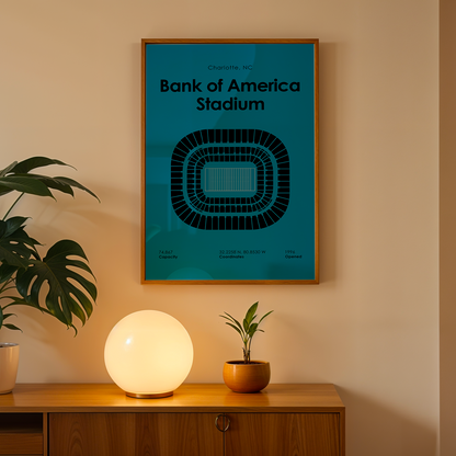 Framed poster of Bank of America Stadium on a wall above a wooden cabinet with decorative items.