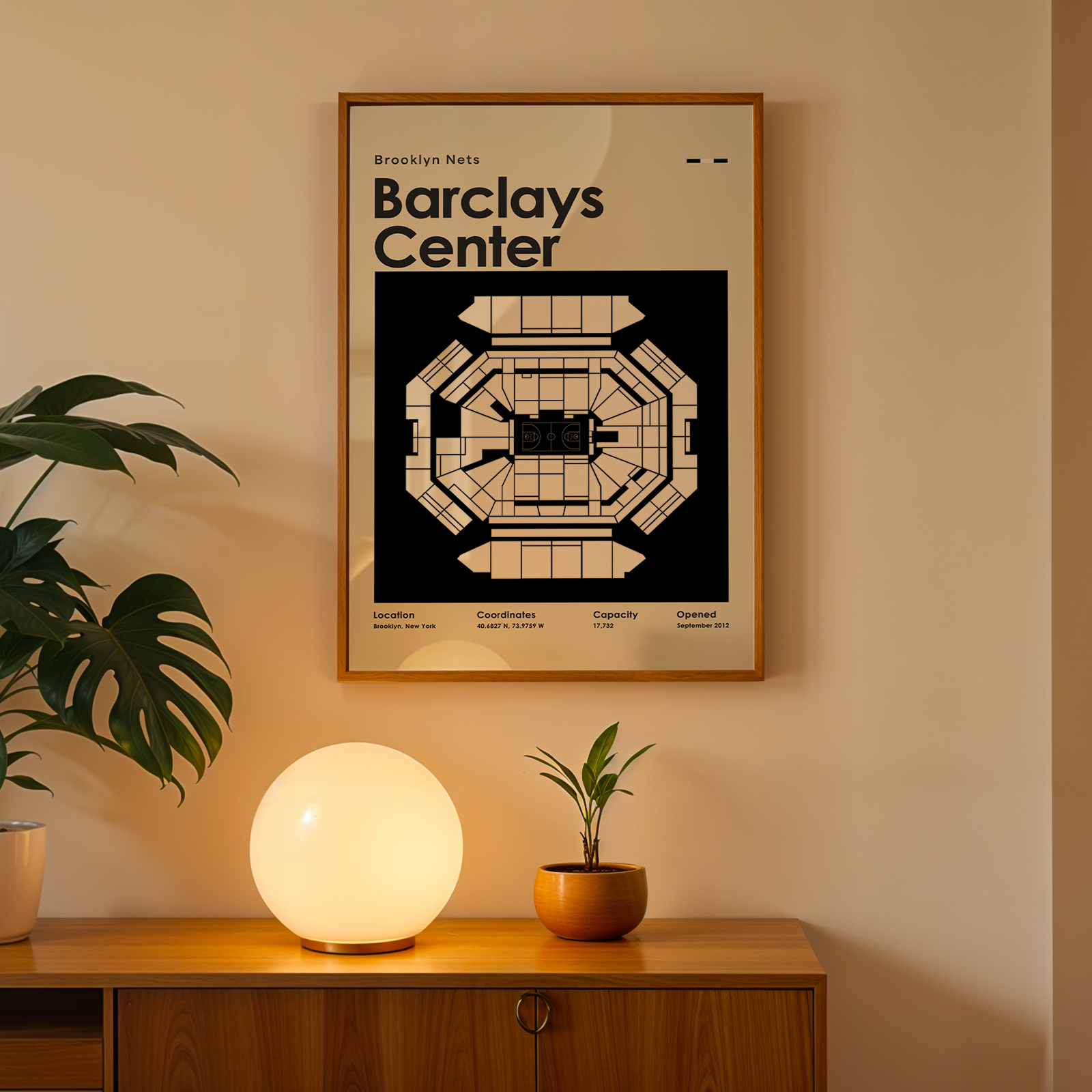 Framed Barclays Center poster on a wall with a table and plants below.