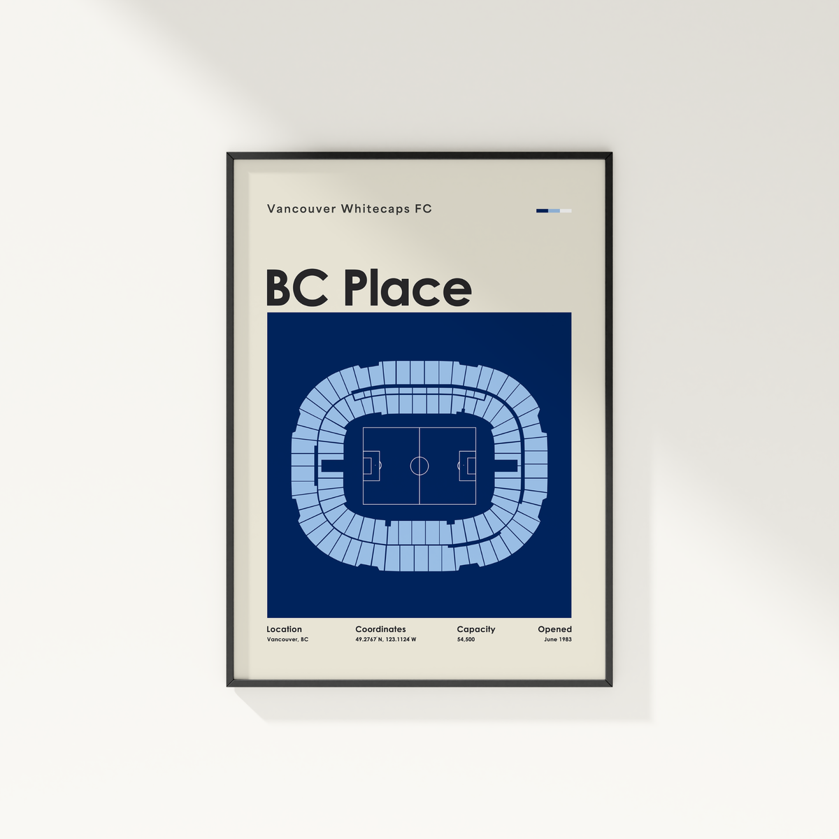 A framed minimalist poster of the Vancouver Whitecaps FC BC Place stadium, featuring a blue and white stadium floor plan on a cream background, hanging on a light gray wall.