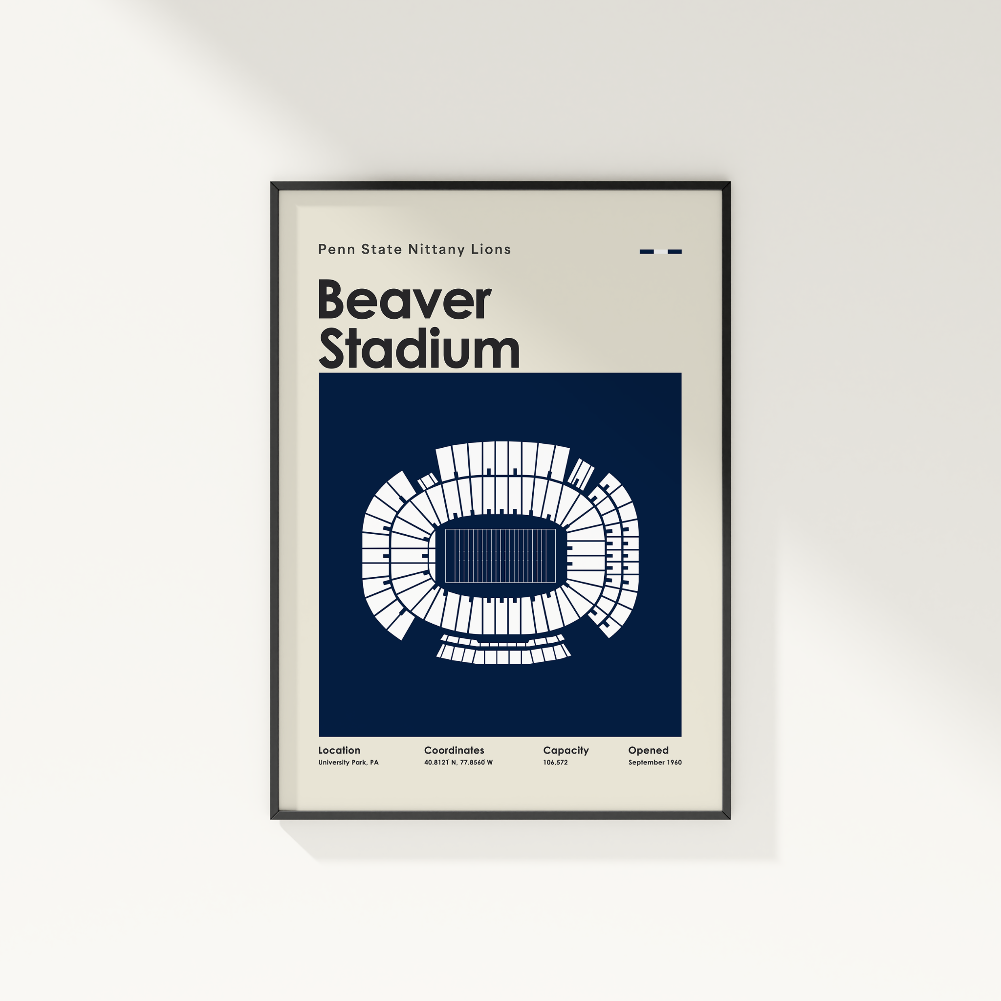 A framed poster of Penn State Nittany Lions Beaver Stadium, featuring a white stadium floor plan on a dark navy blue background, mounted on a light beige wall.