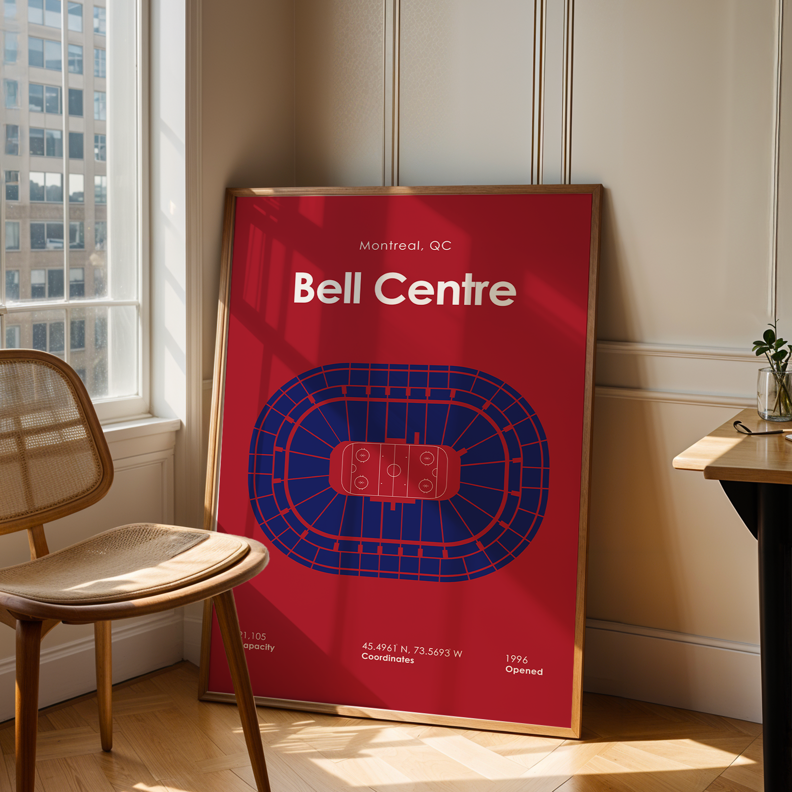 Framed poster of Bell Centre in Montreal, QC leaning against a wall in a room with a chair and window.