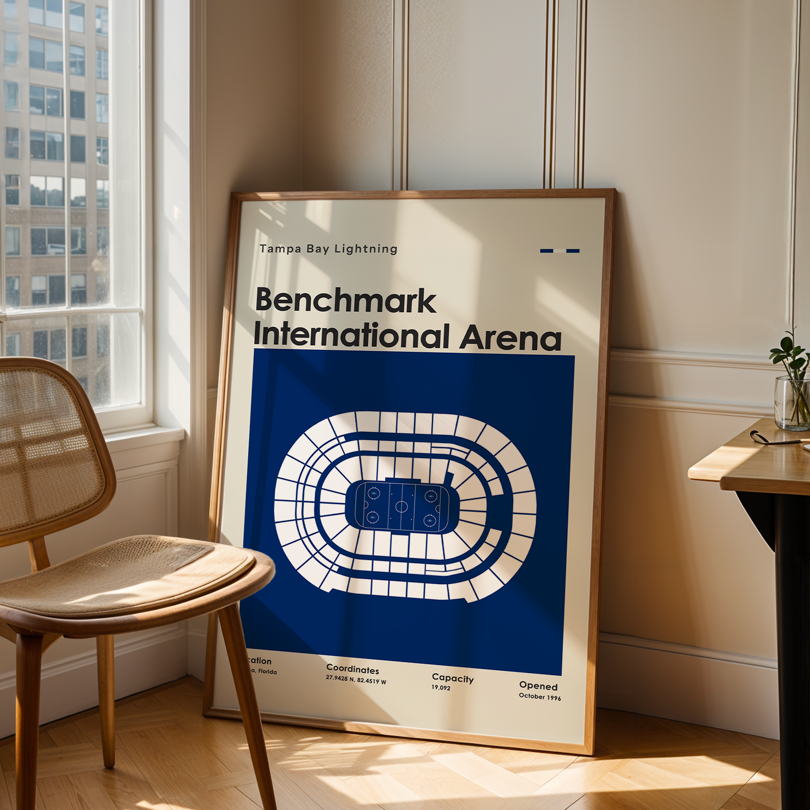 Framed poster of Benchmark International Arena in a room with a chair and table.
