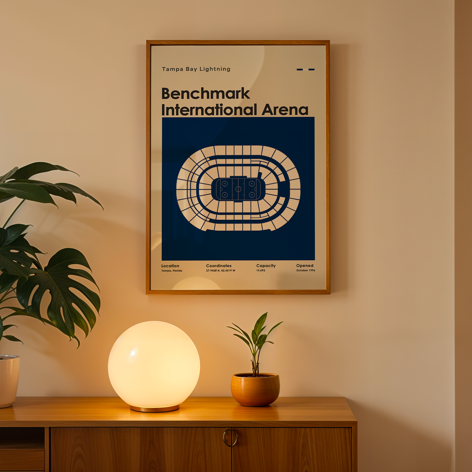Framed poster of Benchmark International Arena on a wall above a wooden cabinet with decorative items.