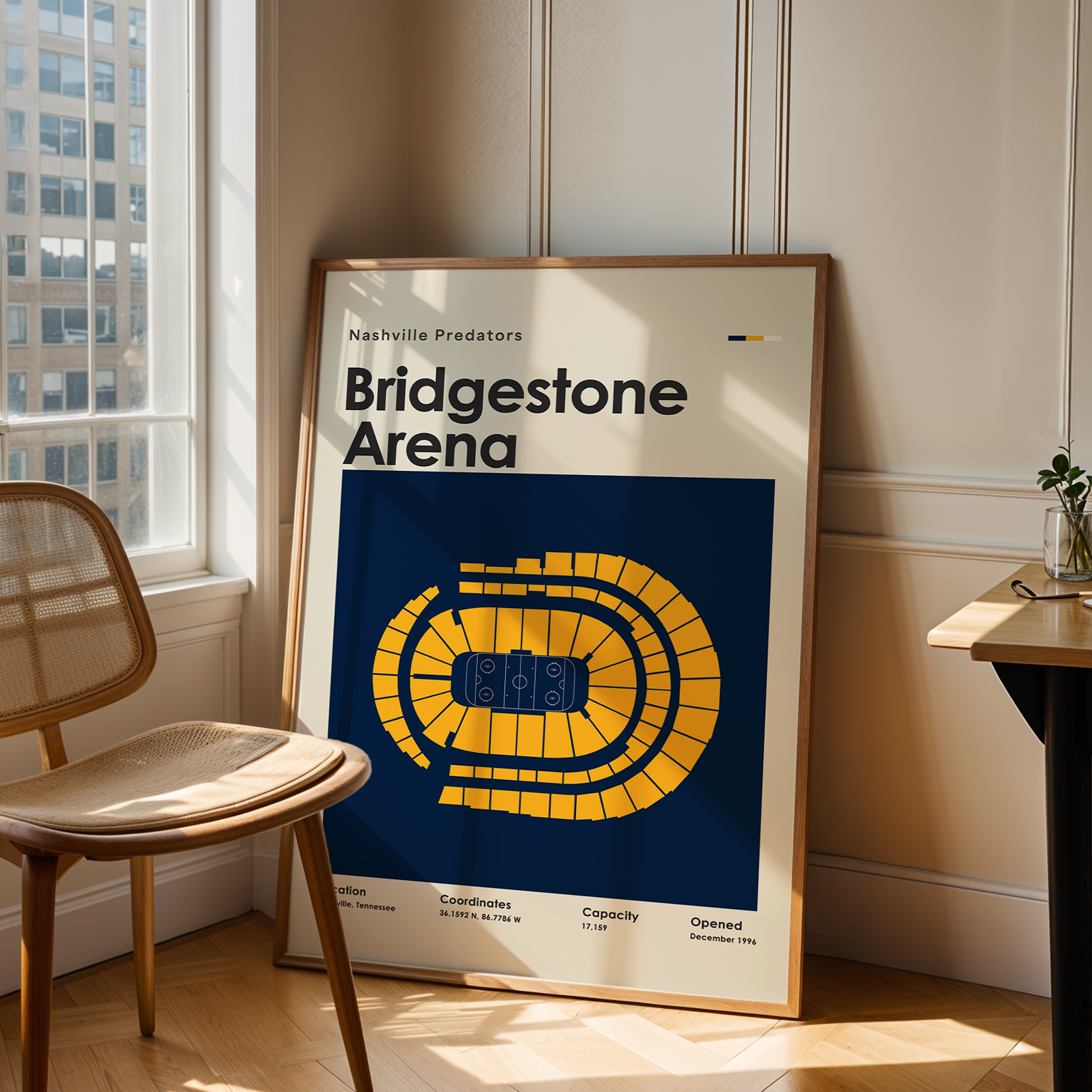 Framed poster of Bridgestone Arena in a room with a chair and table.