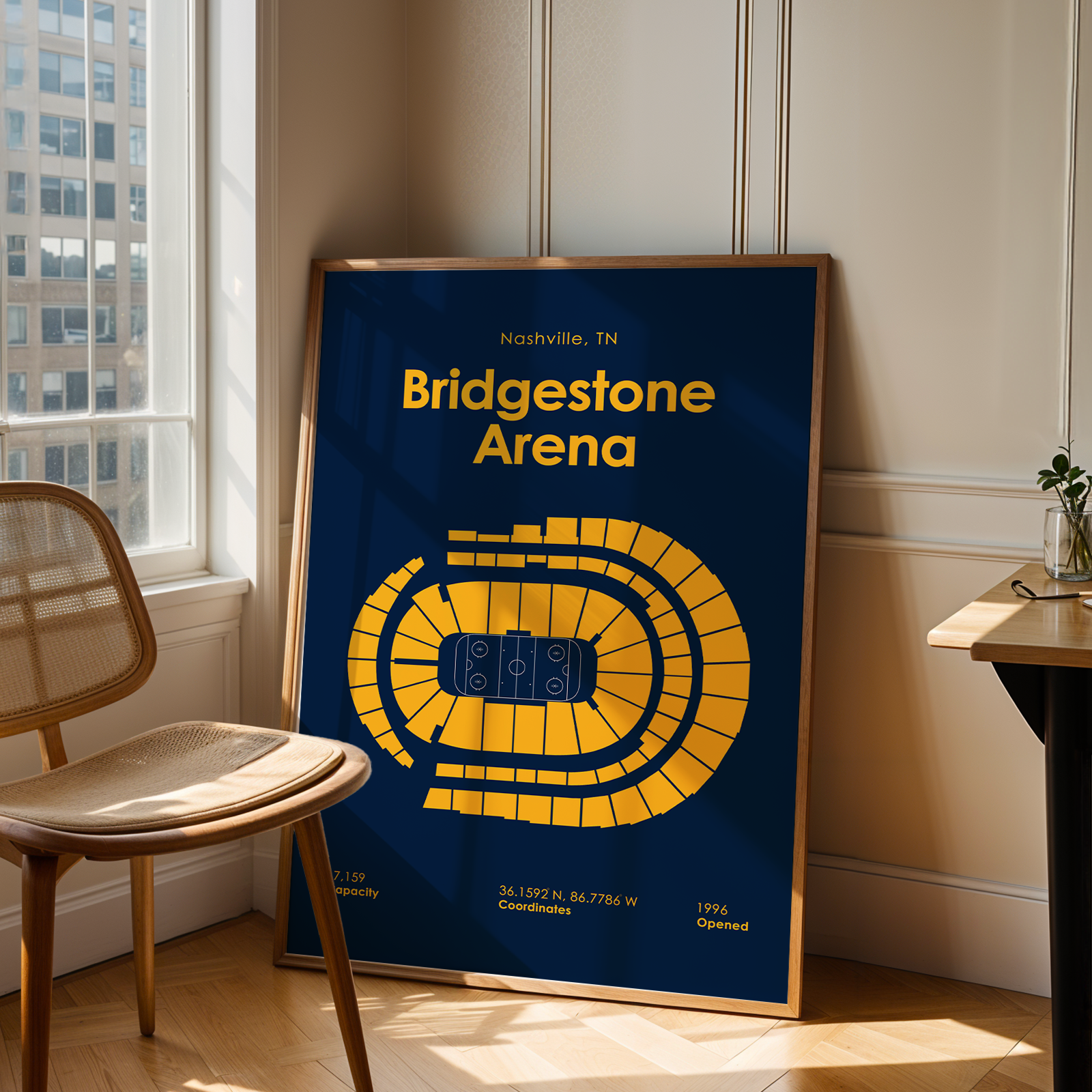 Framed poster of Bridgestone Arena in Nashville, TN, leaning against a wall in a room with a chair and window.