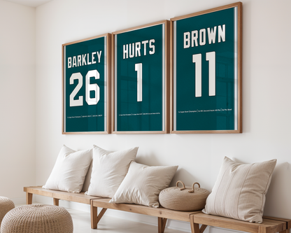 Three framed sports posters with names and numbers on a wall above a wooden bench.