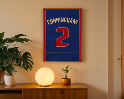 Framed sports jersey with 'Cunningham 2' on a wall above a wooden cabinet with decorative items.