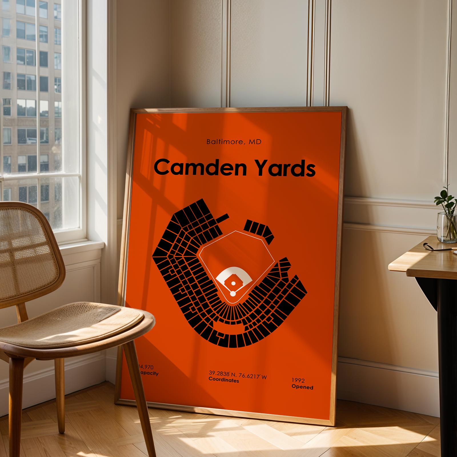 Poster of Camden Yards stadium layout on an orange background in a room with a chair and window.