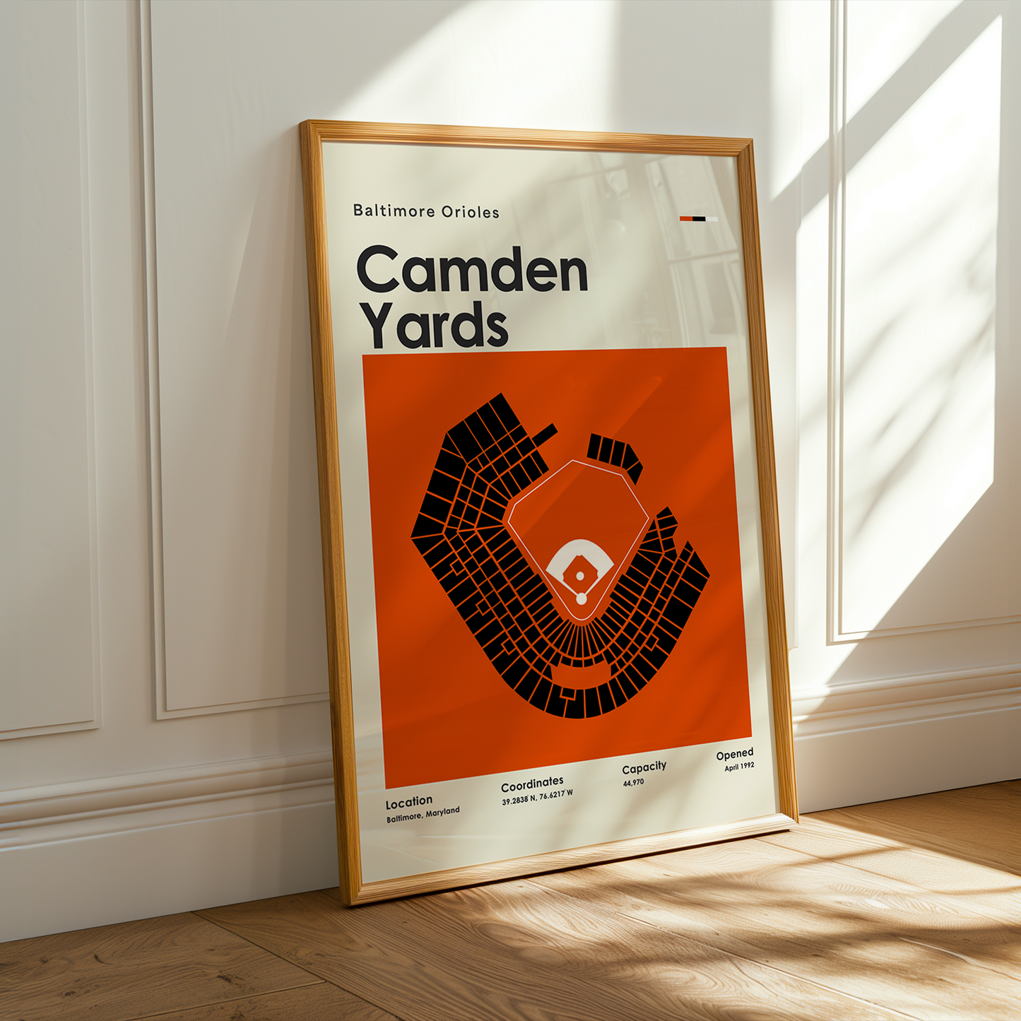 Framed poster of Camden Yards layout on a wall with sunlight casting shadows.
