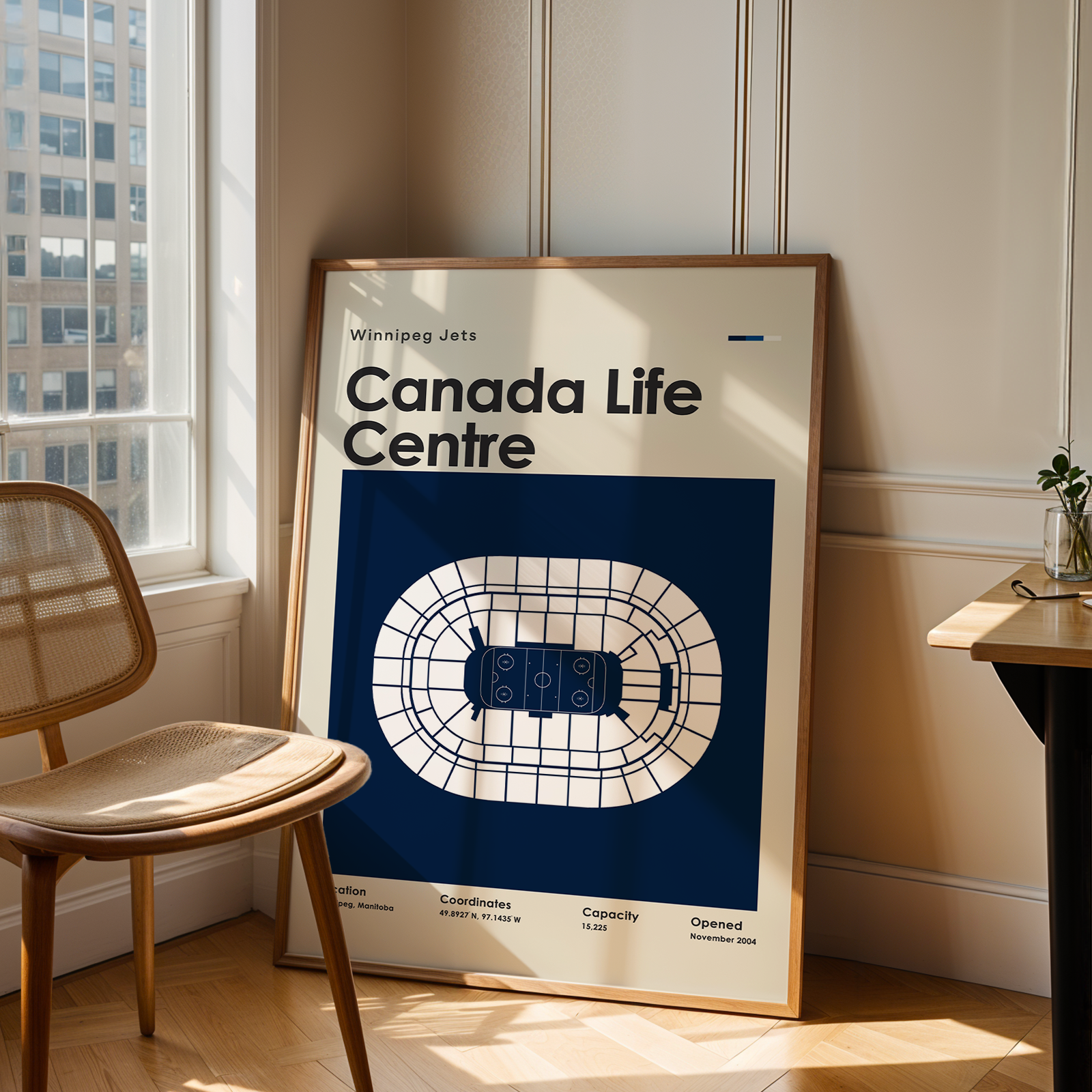 Framed map of Canada Life Centre in a room with a chair and table.