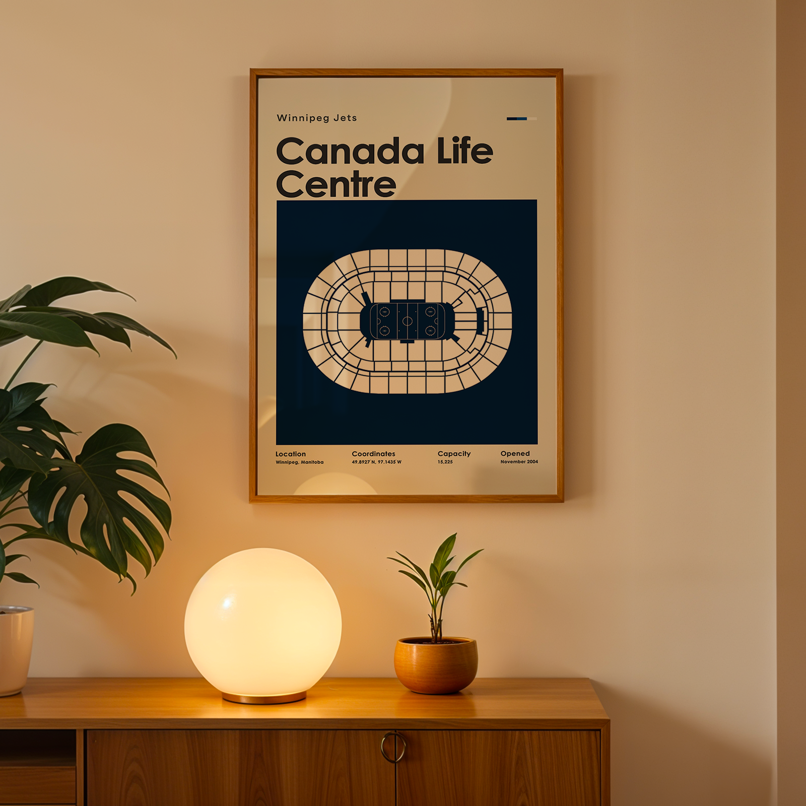 Framed poster of Canada Life Centre on a wall above a wooden cabinet with decorative items.