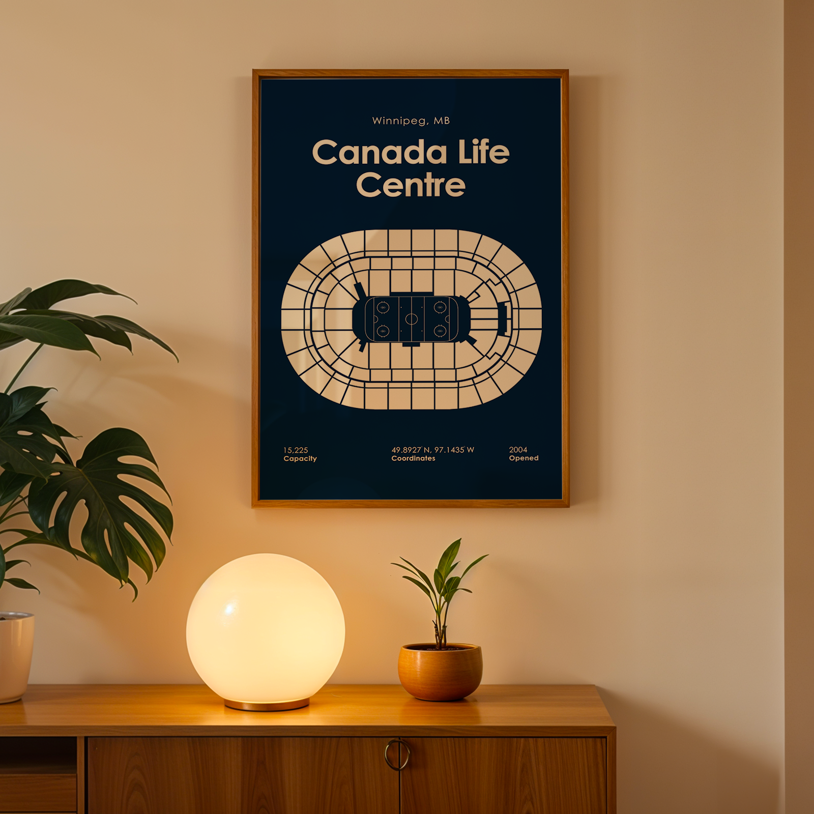 Framed map of Canada Life Centre on a wall with a plant and lamp below.