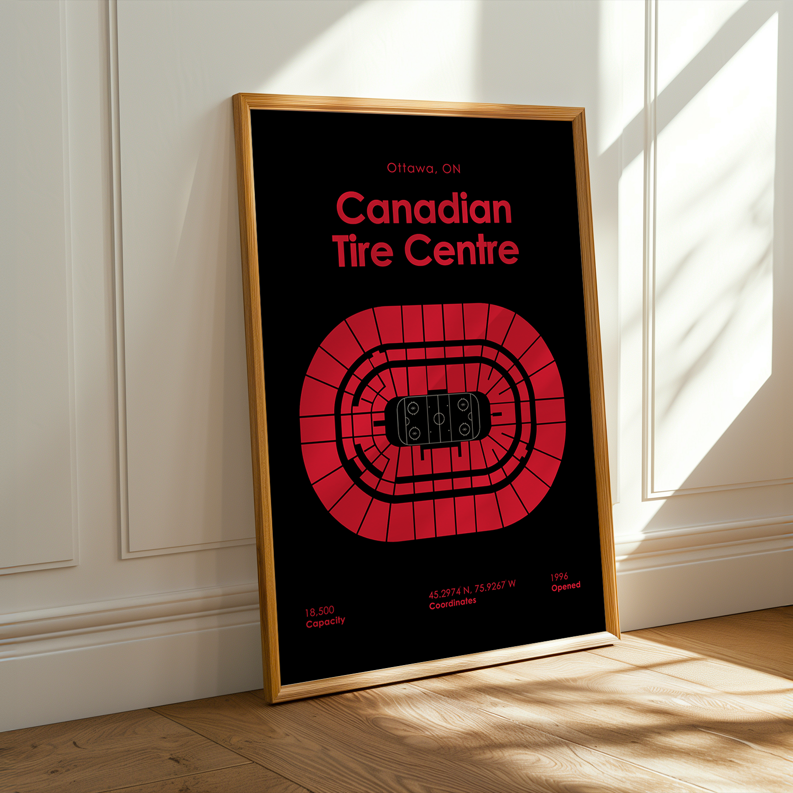 Framed poster of Canadian Tire Centre with red text and logo on a black background, leaning against a white wall.