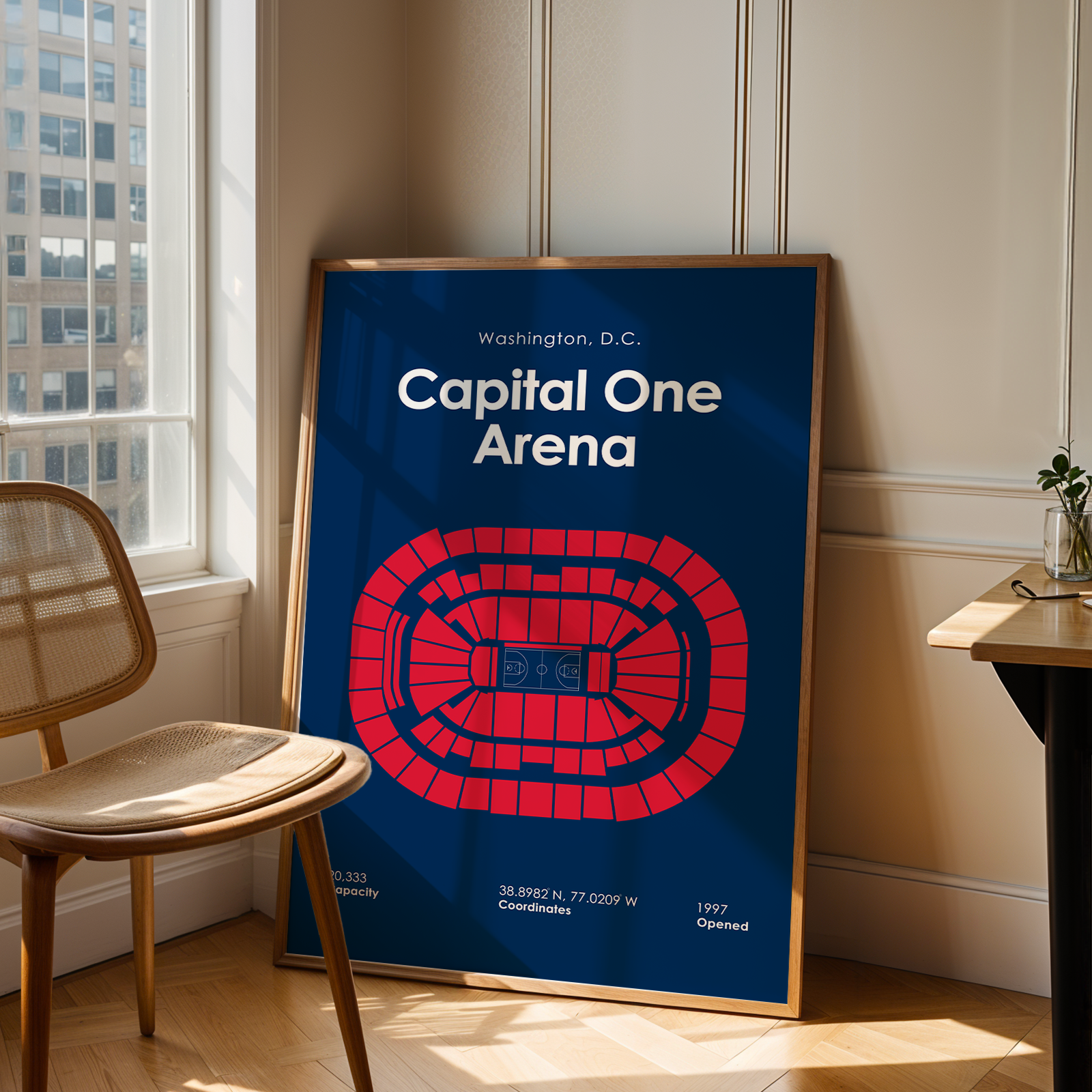Framed poster of Capital One Arena in Washington, D.C. leaning against a wall in a room with a chair and table.