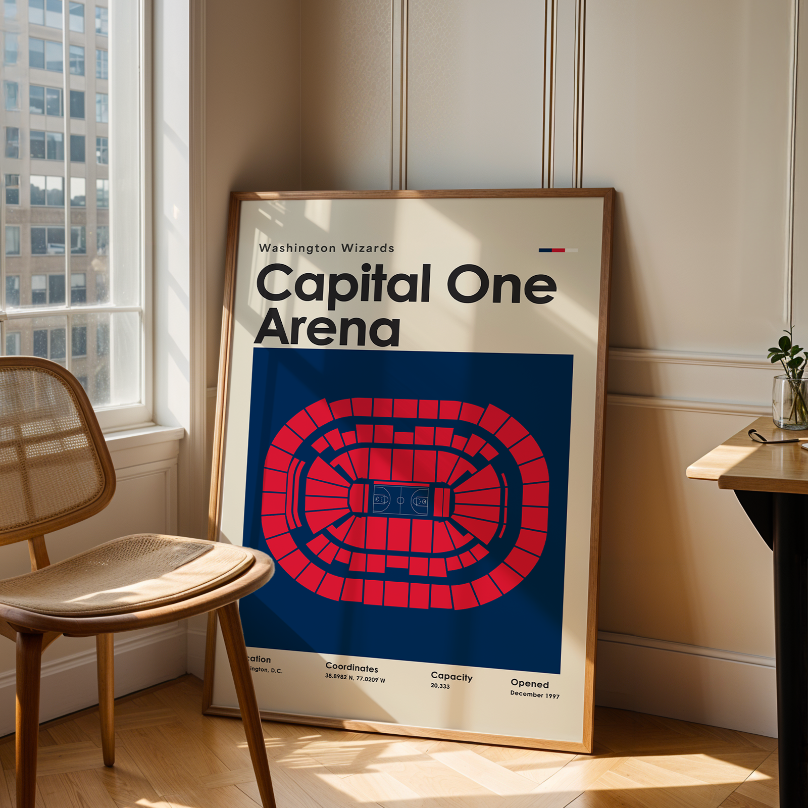 Framed poster of Capital One Arena in a room with a chair and table.
