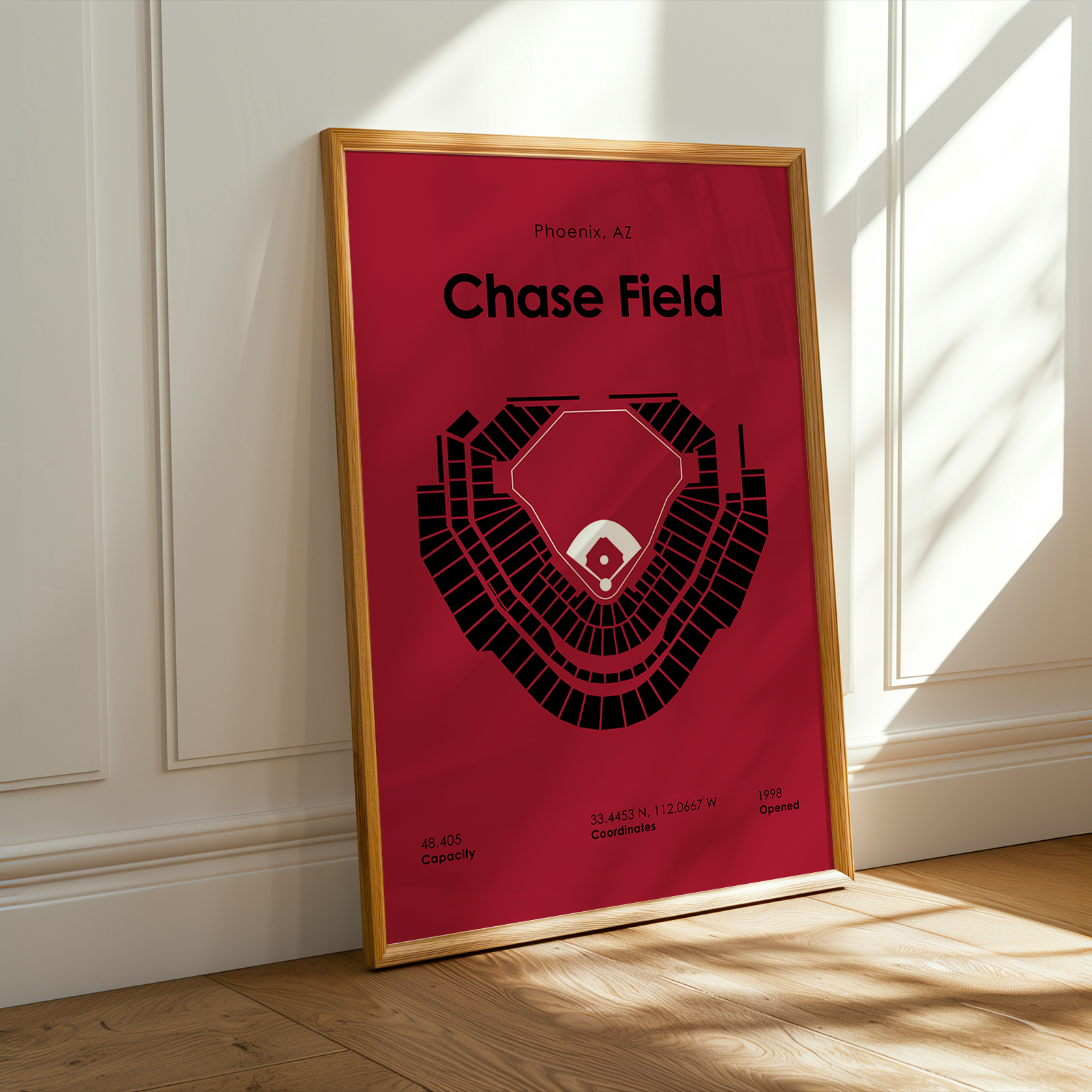 Framed poster of Chase Field layout on a red background, leaning against a white wall.