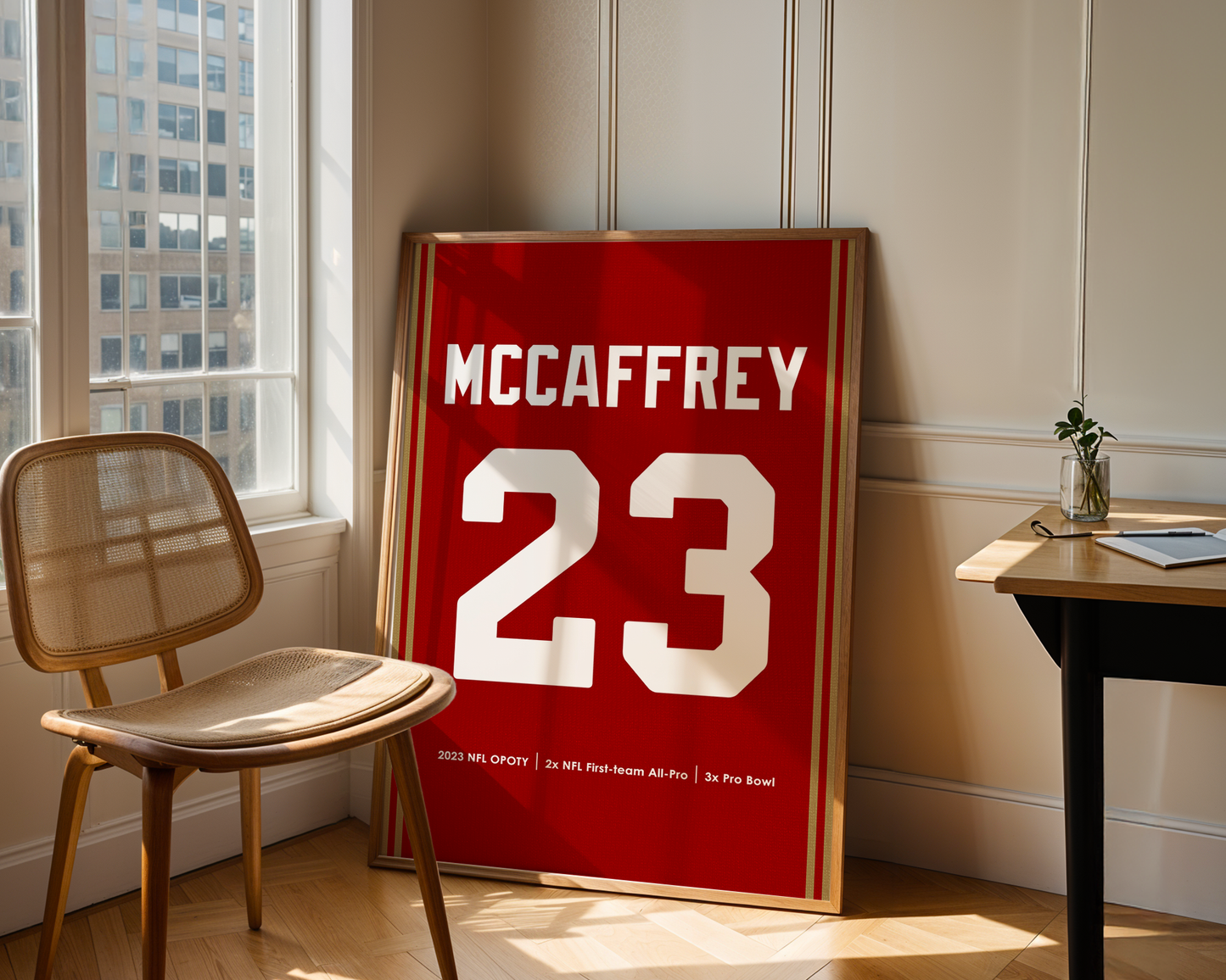 Framed sports jersey with 'McCaffrey 23' in a room with a chair and table.