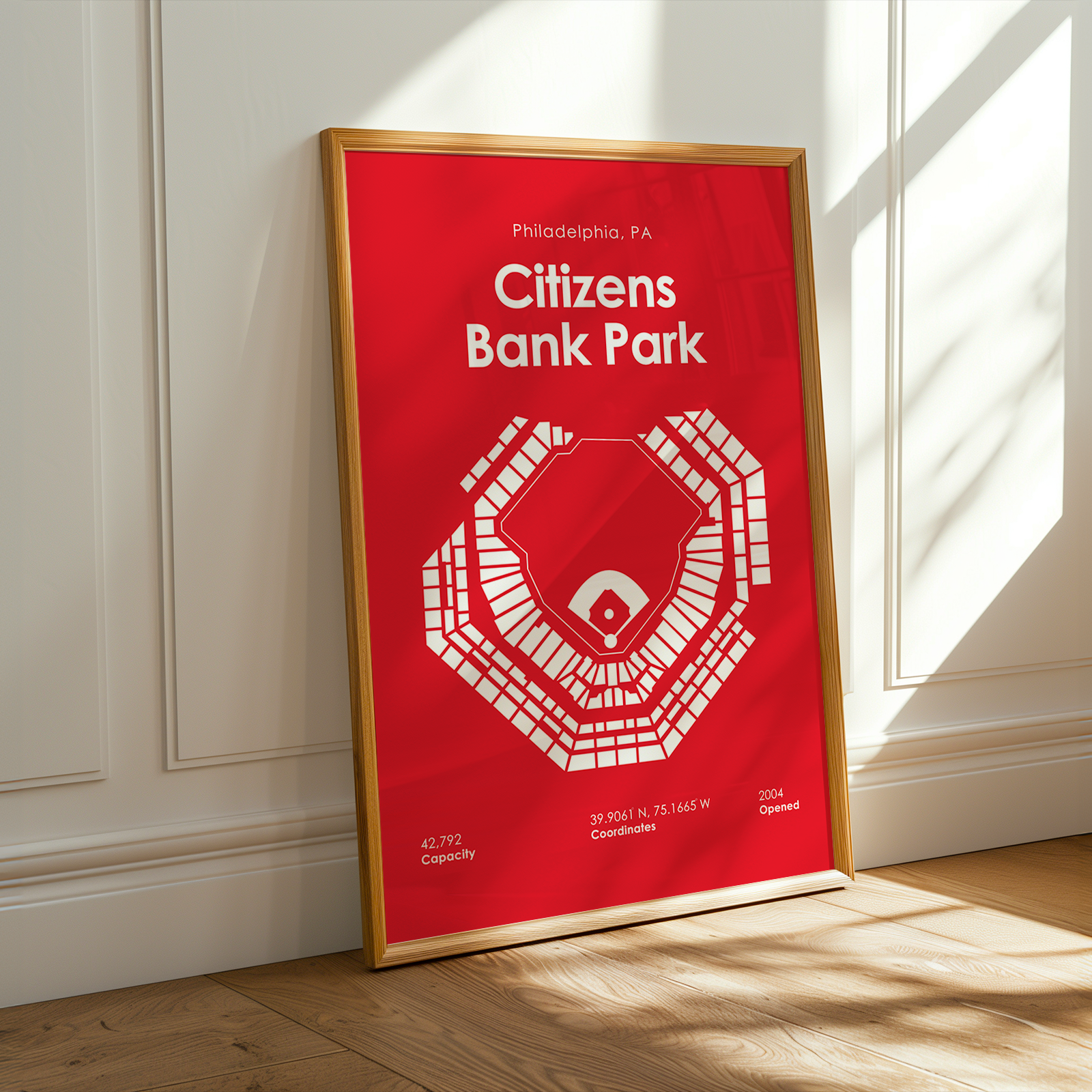Framed poster of Citizens Bank Park on a wall with sunlight casting shadows.