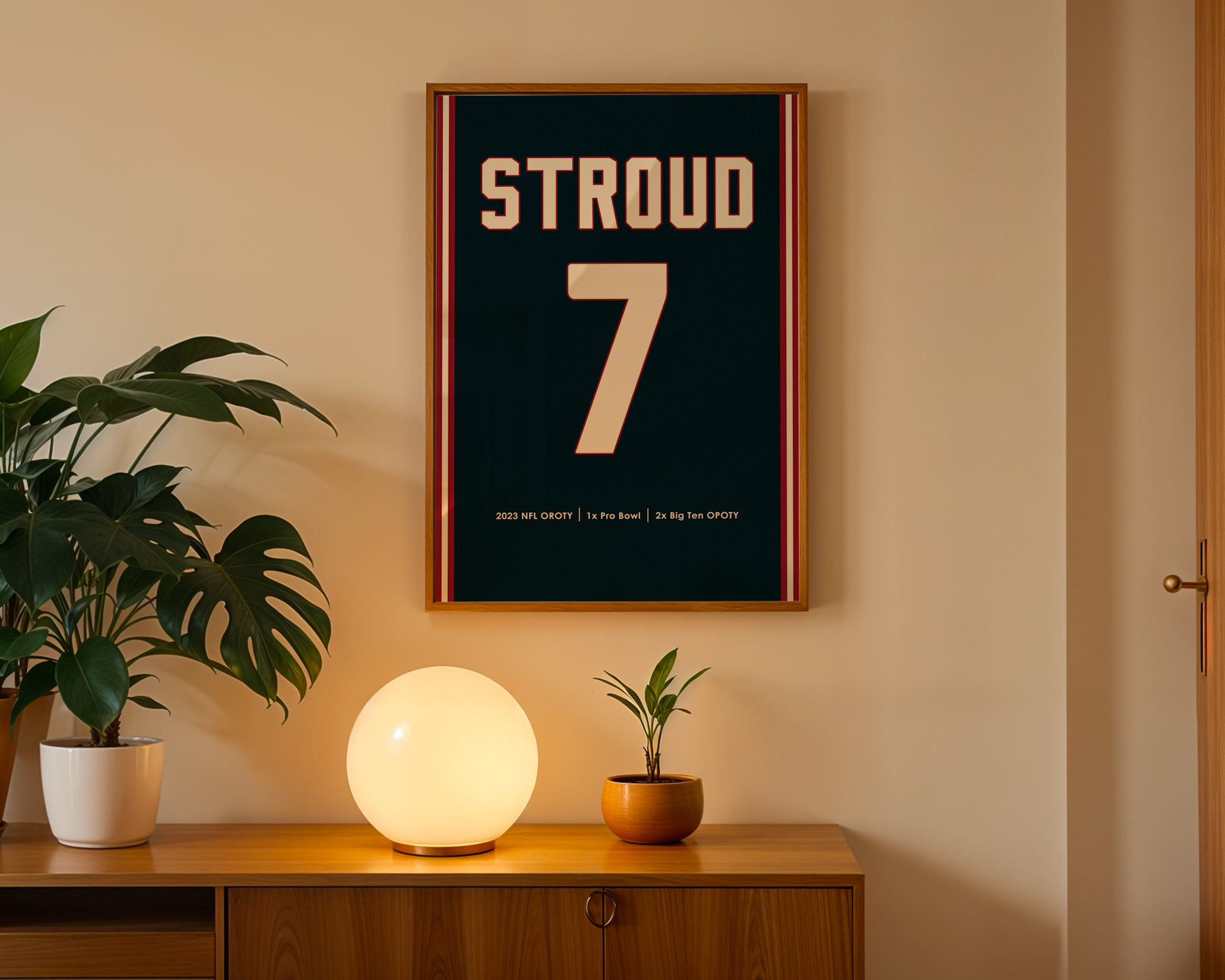 Framed poster with 'STROUD 7' on a wall above a wooden cabinet with decorative items.