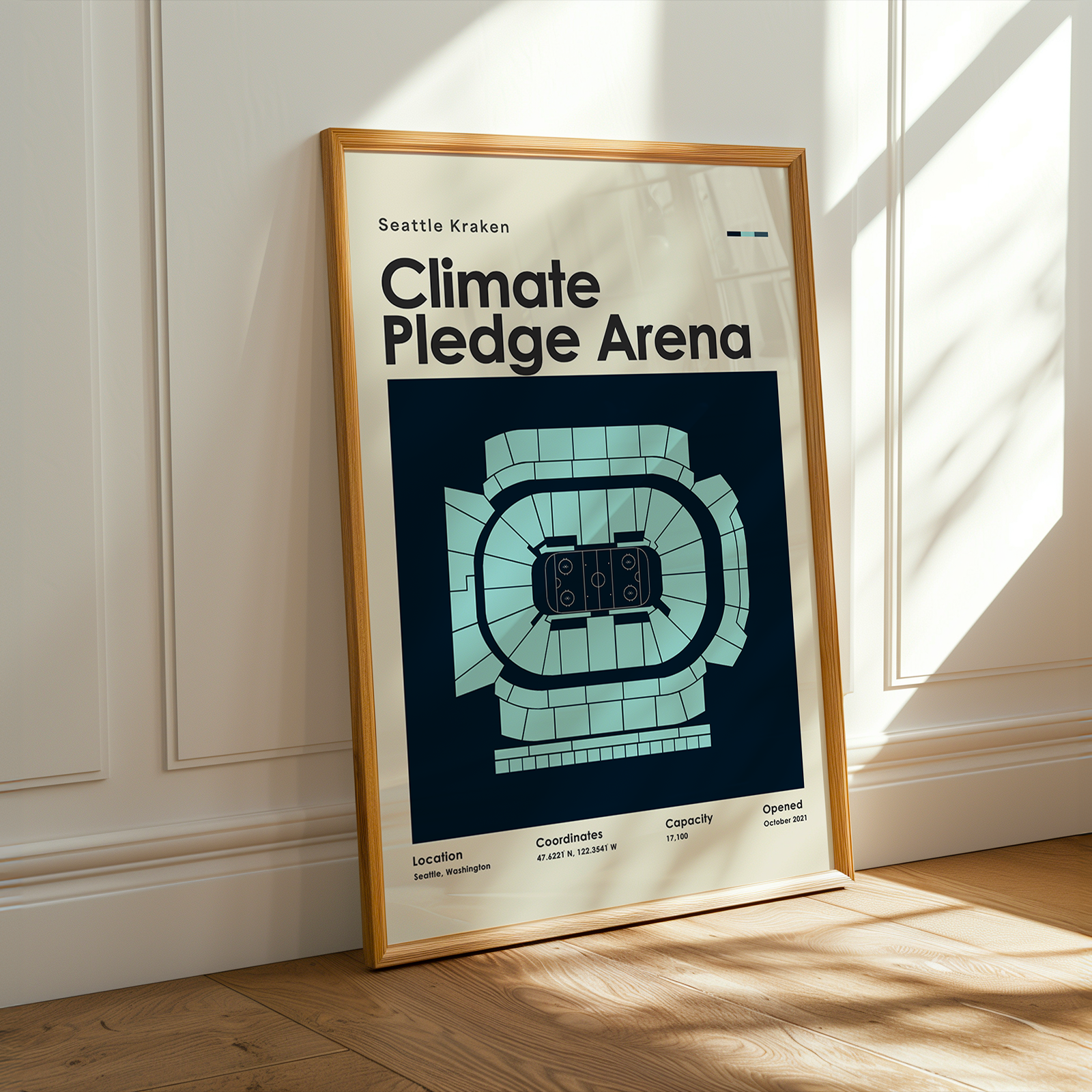 Framed poster of Climate Pledge Arena with wooden frame on a light-colored wall.