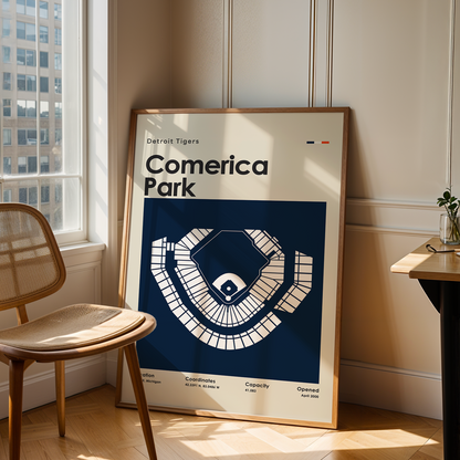 Framed poster of Comerica Park in a room with a chair and table.