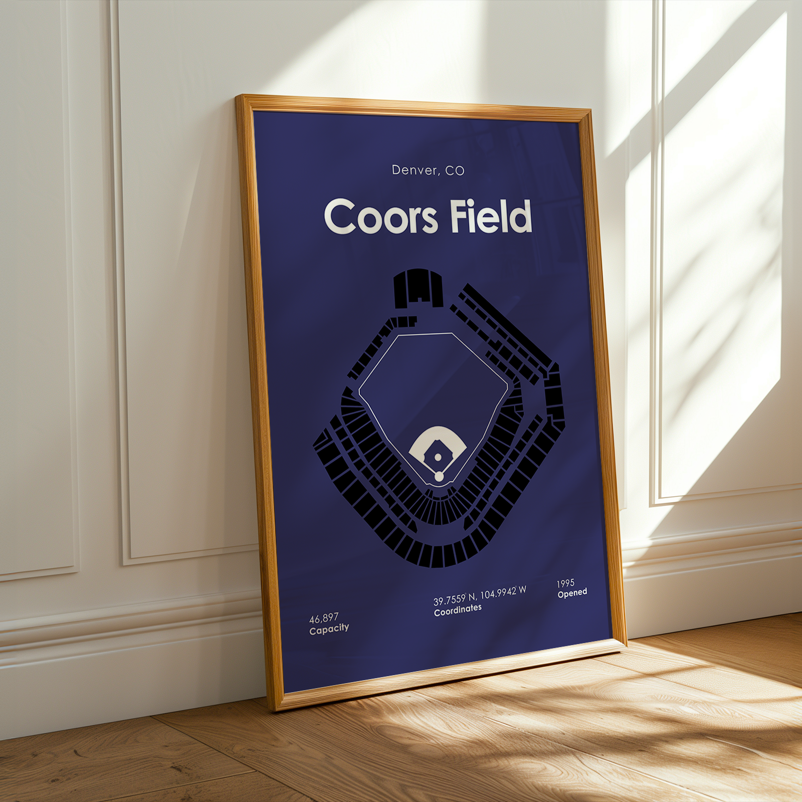 Framed poster of Coors Field layout on a wall with sunlight casting shadows.