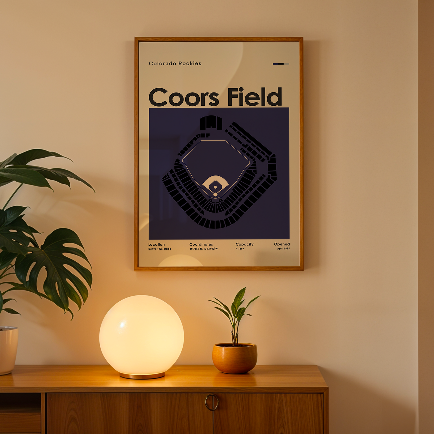 Framed Coors Field poster on a wall above a wooden cabinet with decorative items.