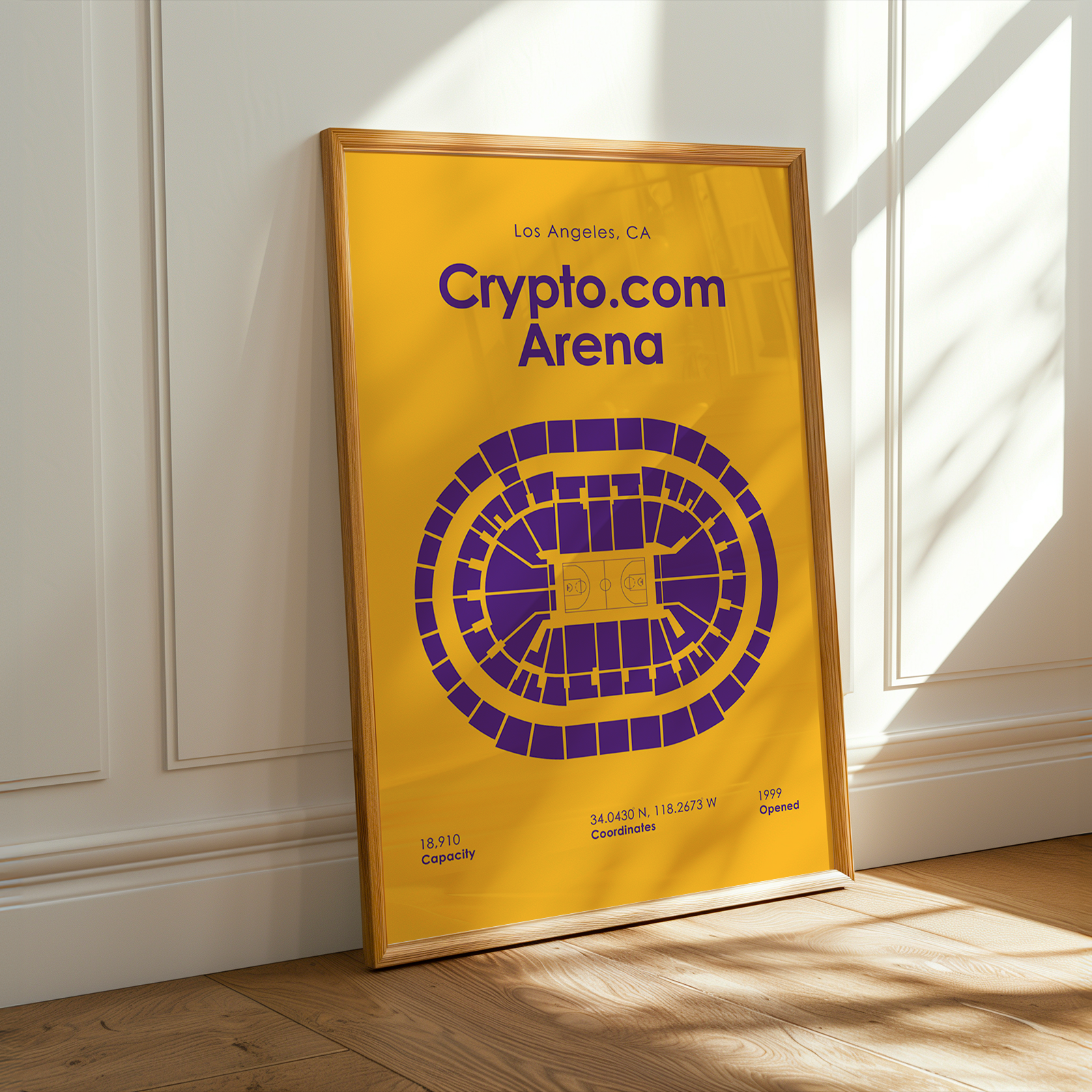 Framed poster of Crypto.com Arena in Los Angeles on a wooden floor with sunlight streaming in.