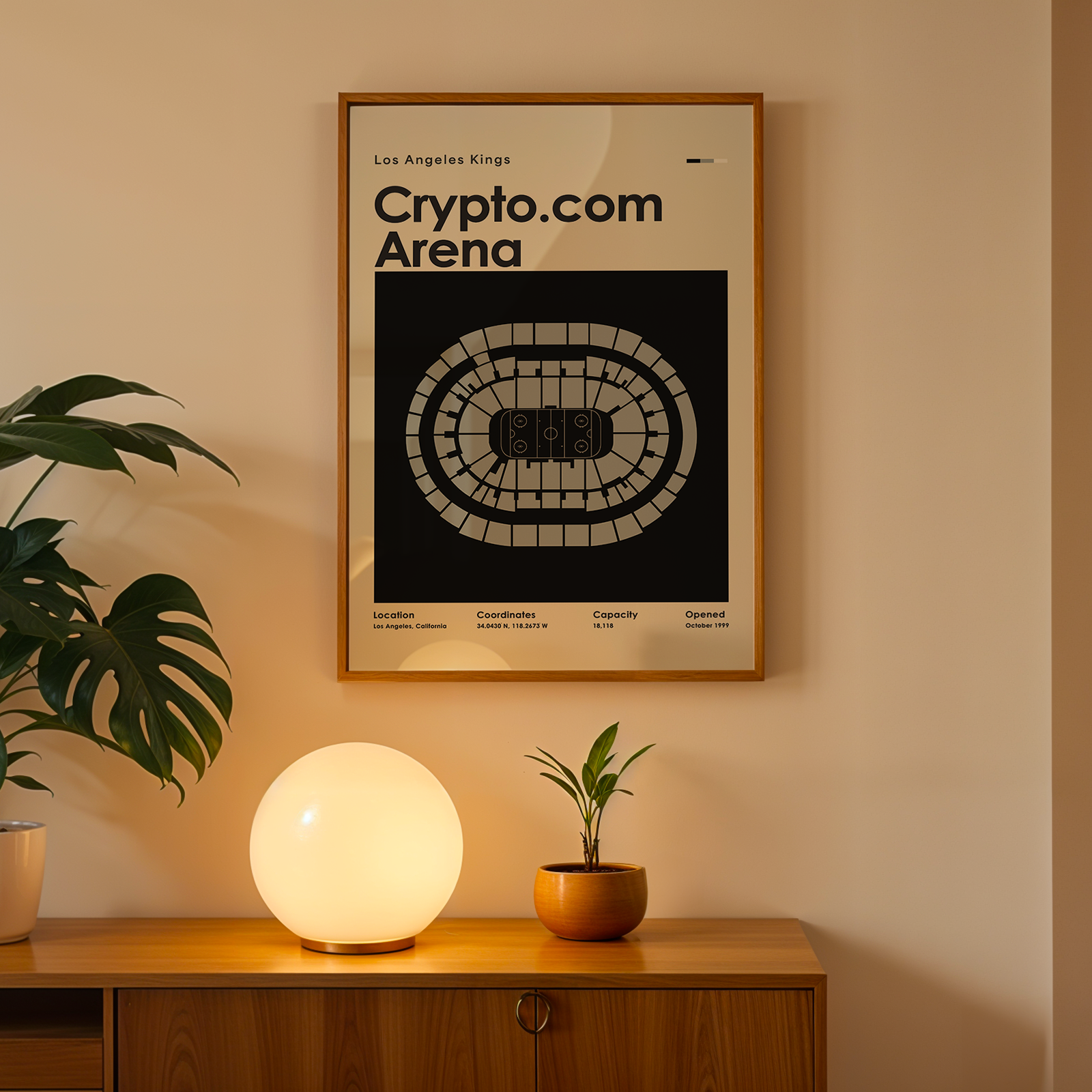 Framed poster of Crypto.com Arena on a wall above a wooden cabinet with decorative items.