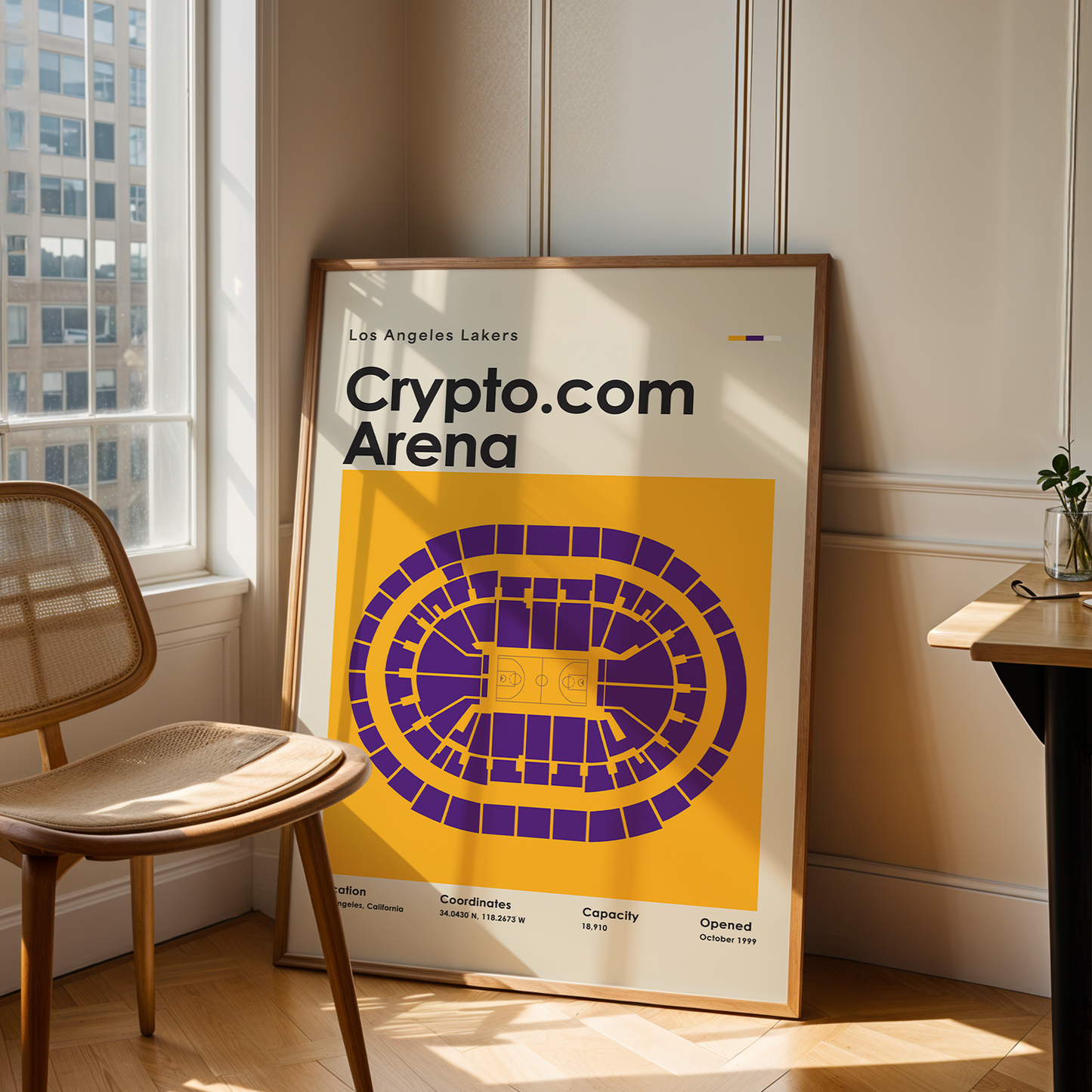 Framed poster of Crypto.com Arena in a room with a chair and table.