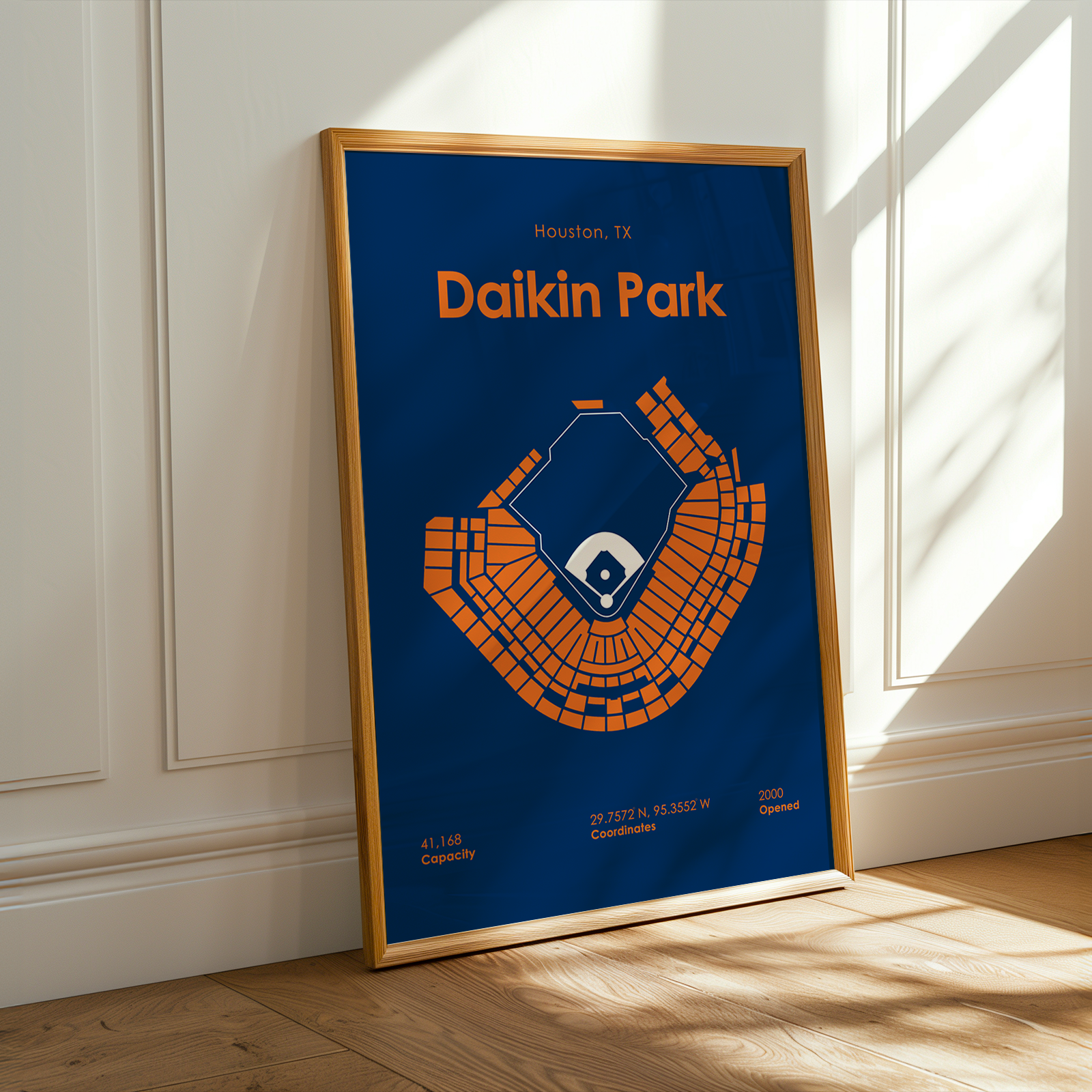 Framed poster of Daikin Park with blue background and orange design, leaning against a white wall.