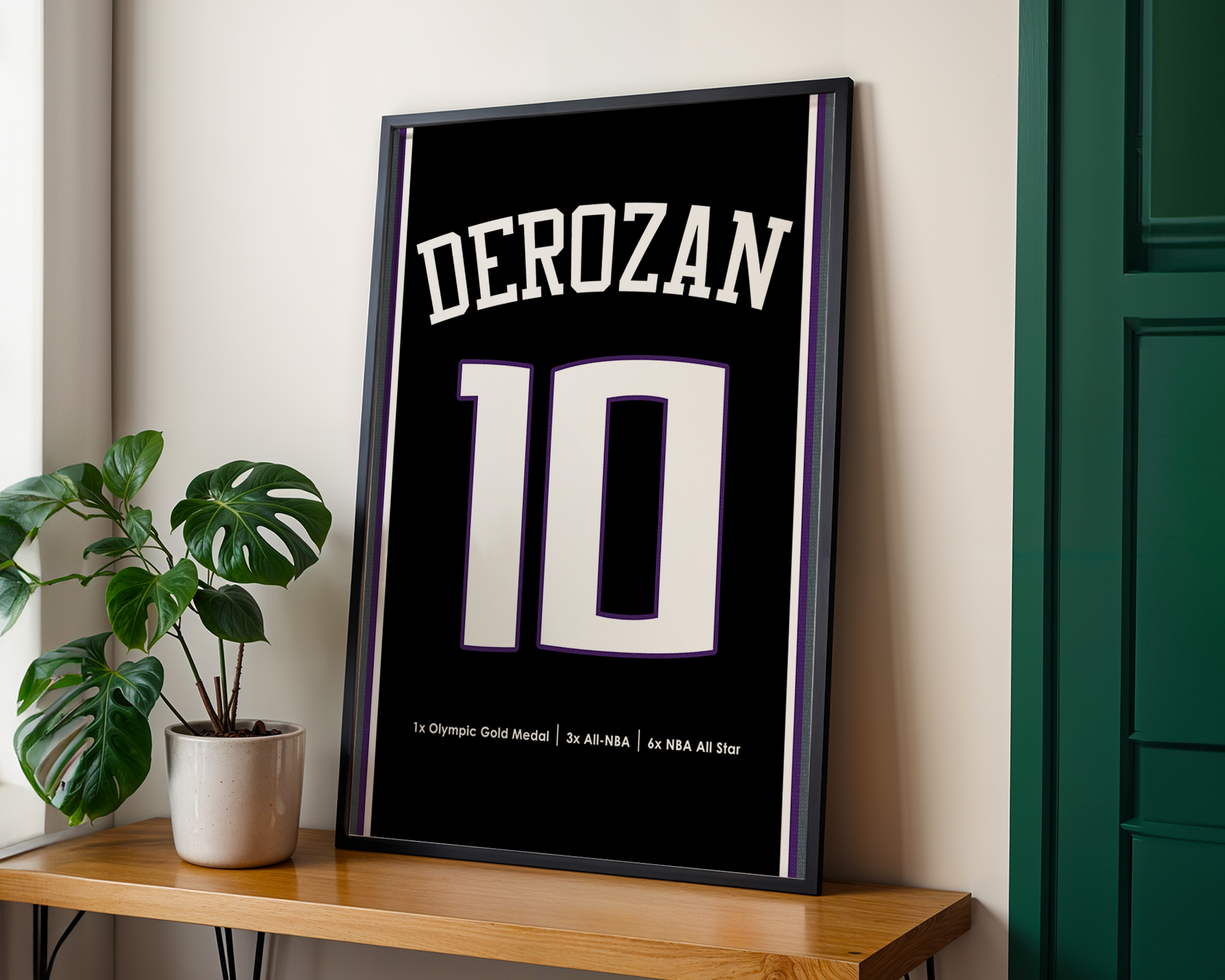 Framed poster with 'DEROZAN' and number '10' on a wooden table with a plant in the background