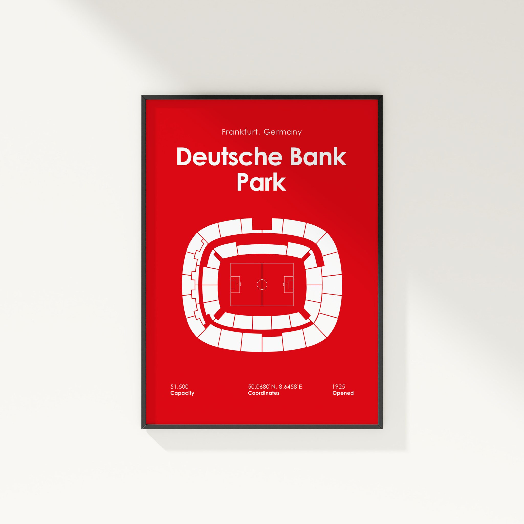 A framed red and white poster of Deutsche Bank Park in Frankfurt, Germany, featuring a minimalist stadium floor plan and text details, shown hanging on a light gray wall.