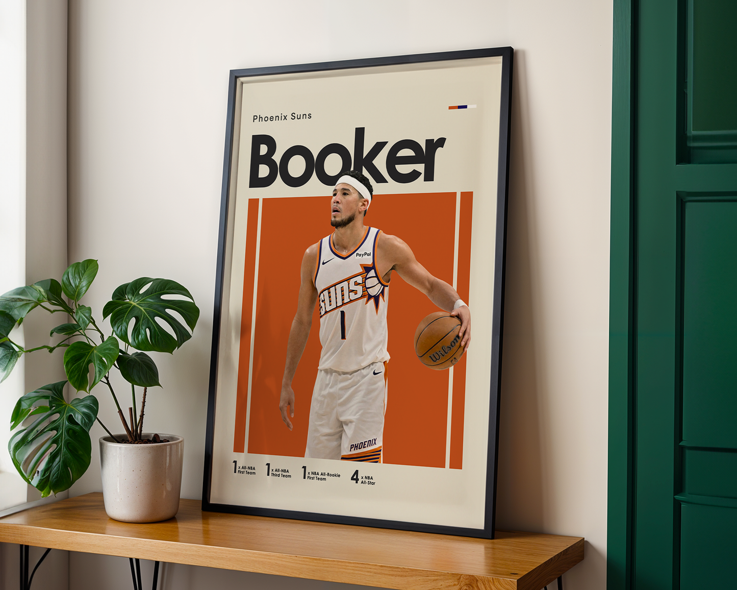 Framed poster of a basketball player on a wooden shelf with a plant and green door in the background
