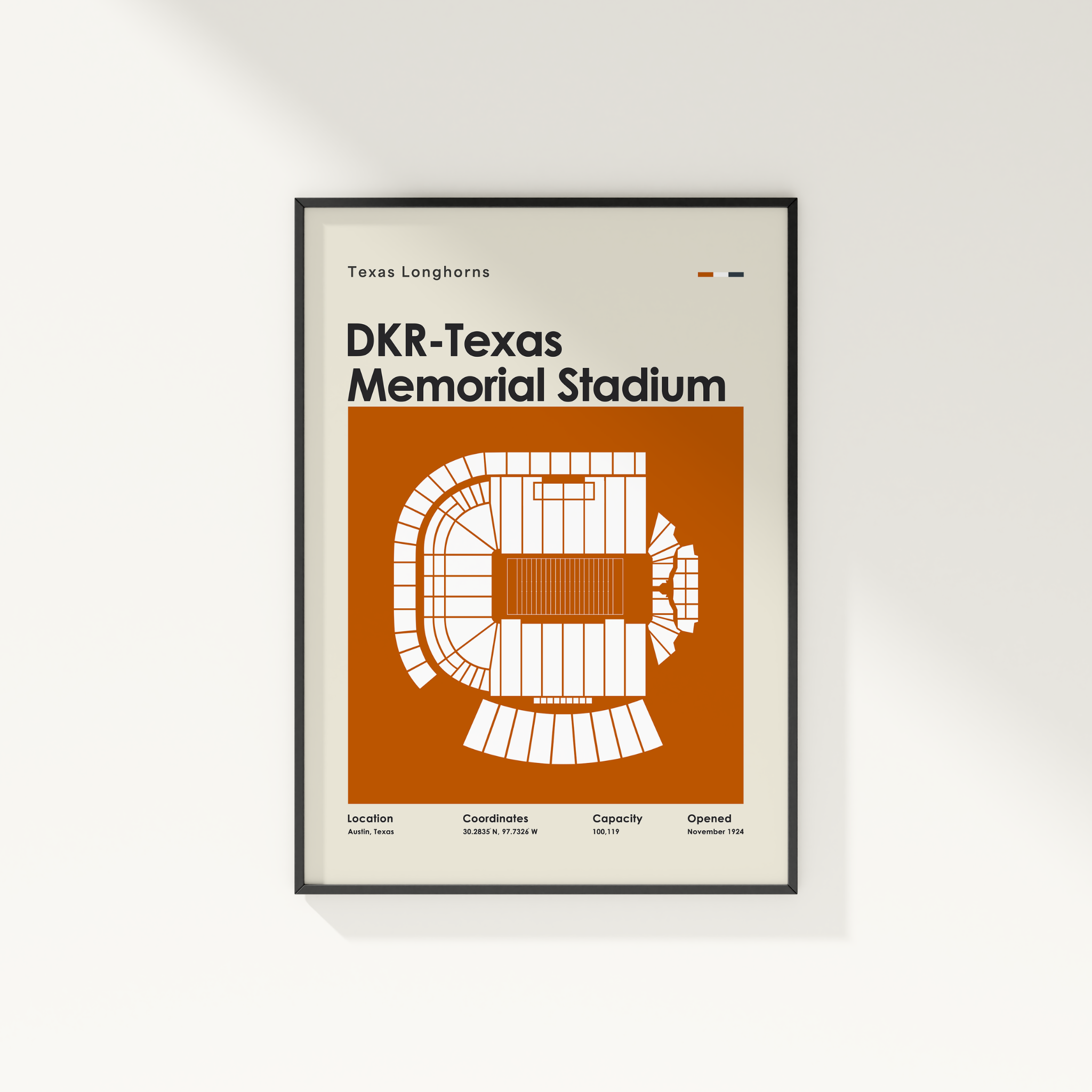 A framed minimalist poster of the Texas Longhorns and DKR-Texas Memorial Stadium, featuring a white venue floor plan on an orange background, mounted on a light beige wall.