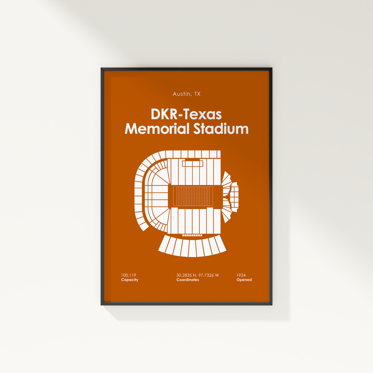 A framed minimalist stadium floor plan poster for DKR-Texas Memorial Stadium in Austin, TX, featuring a white schematic on a burnt orange background, shown hanging on a light wall.