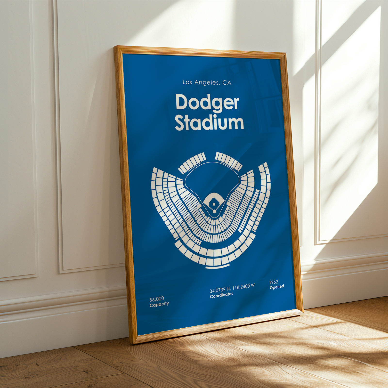 Framed poster of Dodger Stadium layout on a blue background, leaning against a white wall.