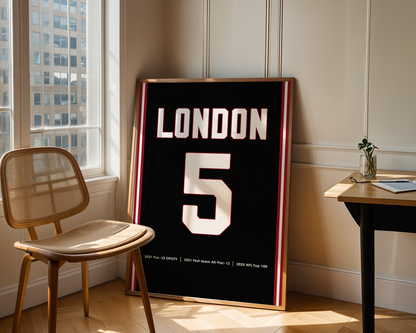 Framed poster with 'LONDON 5' in a room with a chair and table.