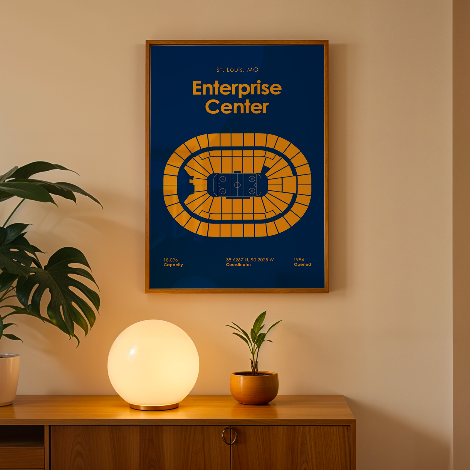 Framed poster of the Enterprise Center on a wall above a wooden cabinet with decorative items.