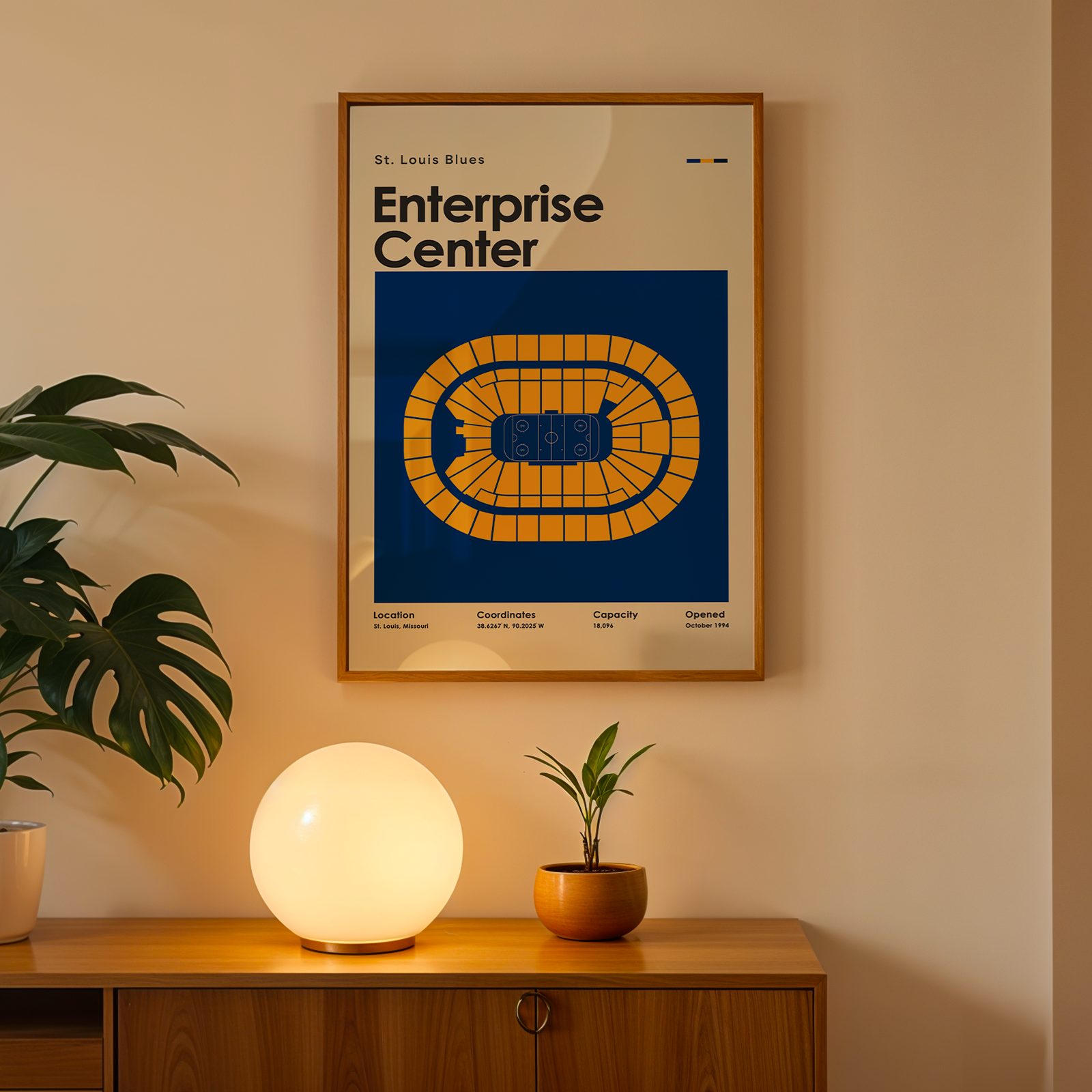 Framed poster of Enterprise Center on a wall above a wooden cabinet with decorative items.
