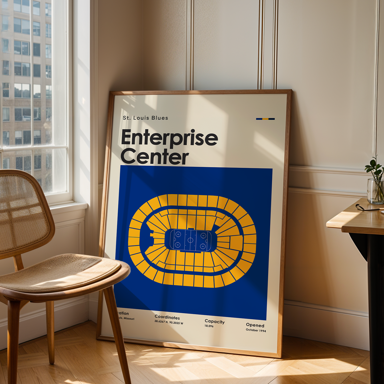 Framed poster of Enterprise Center in a room with a chair and table.