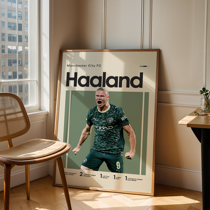 Framed poster of a soccer player with 'Haaland' on a wall in a room with a chair and table.