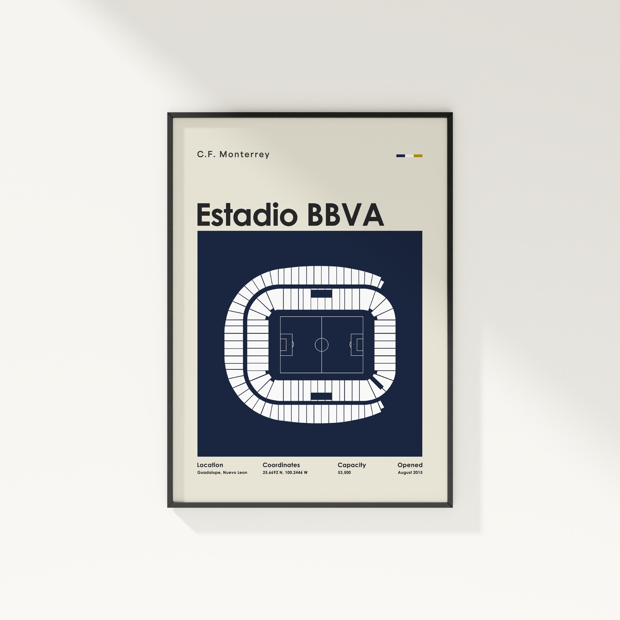 A framed minimalist poster of the Estadio BBVA in Monterrey, Mexico, featuring a white stadium floor plan on a navy blue background, mounted on a light gray wall.