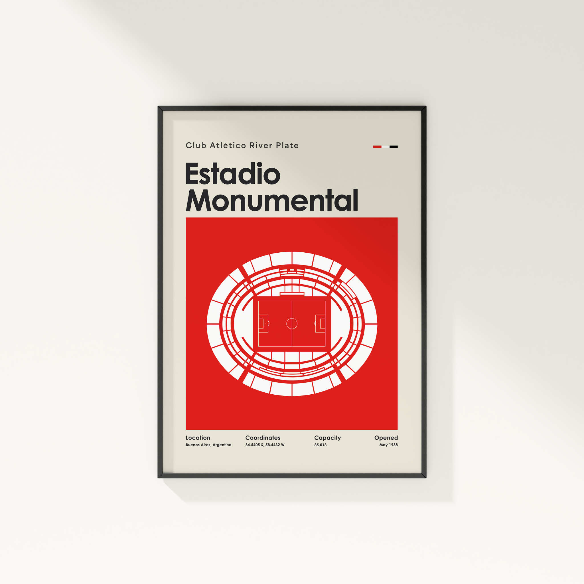 A framed minimalist sports poster of Estadio Monumental from Club Atlético River Plate, featuring a bold red and white stadium diagram on a cream background, shown hanging on a light gray wall.