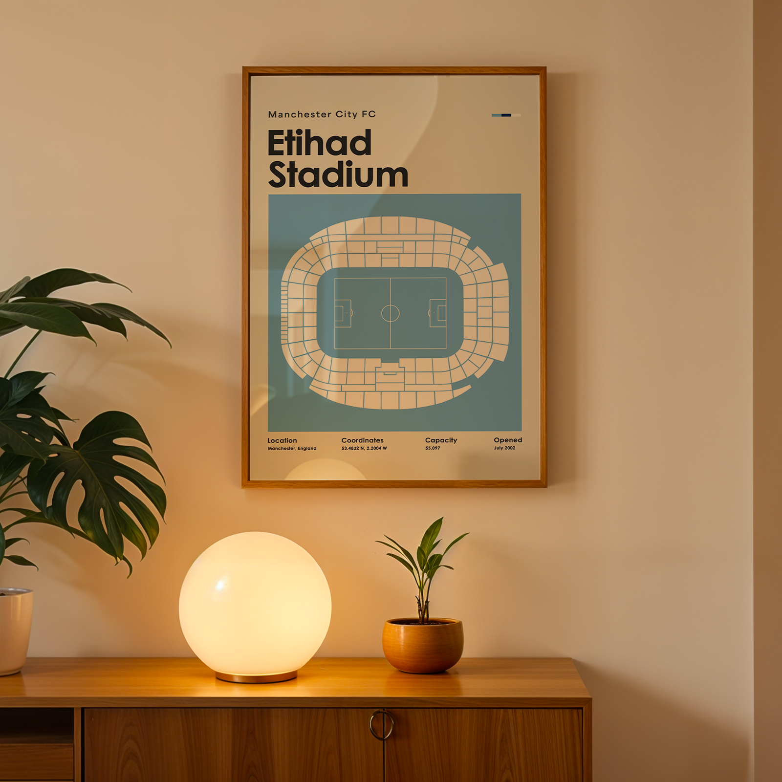 Framed poster of Etihad Stadium on a wall with a wooden cabinet and decorative items.