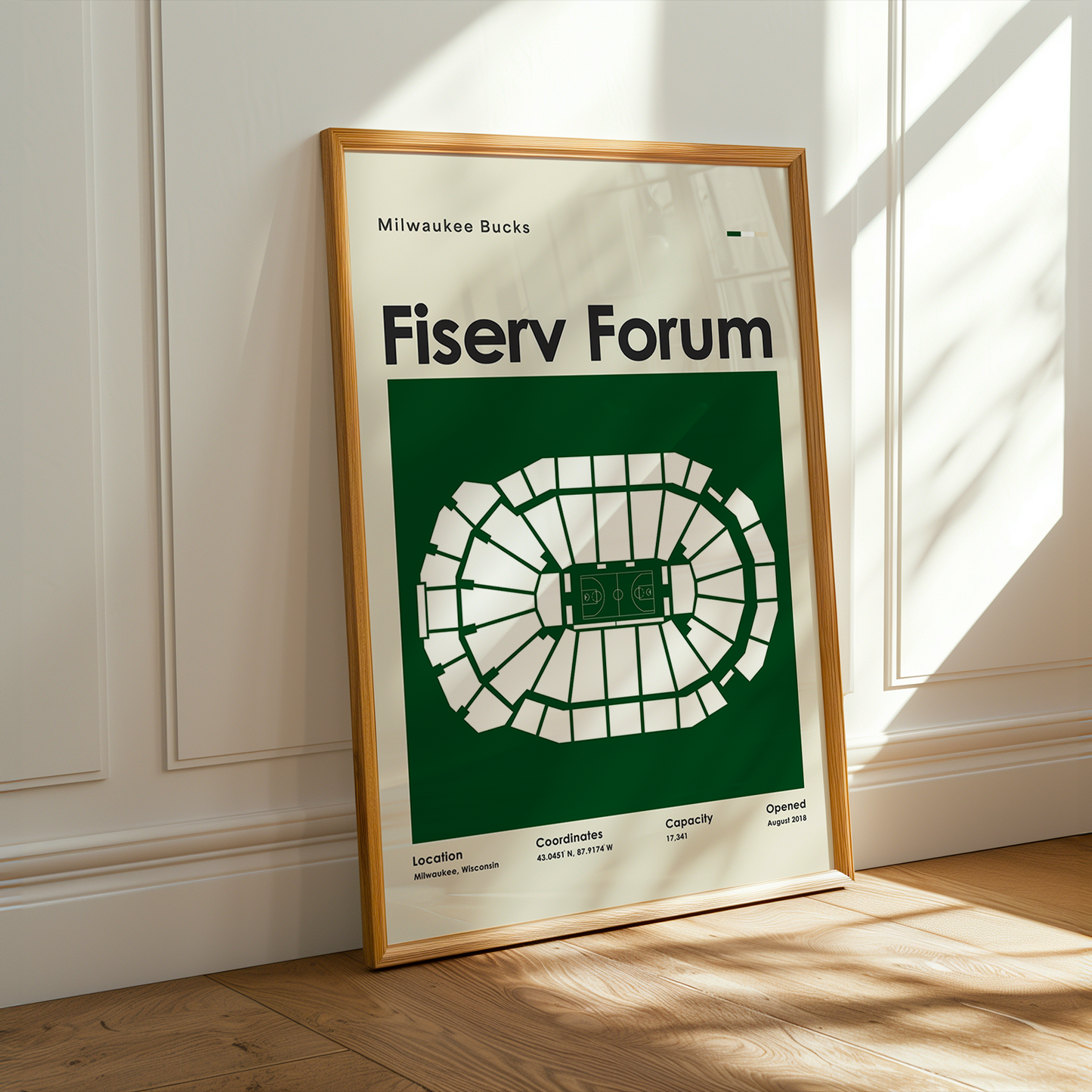Fiserv Forum poster in a wooden frame on a light wooden floor with a white wall background