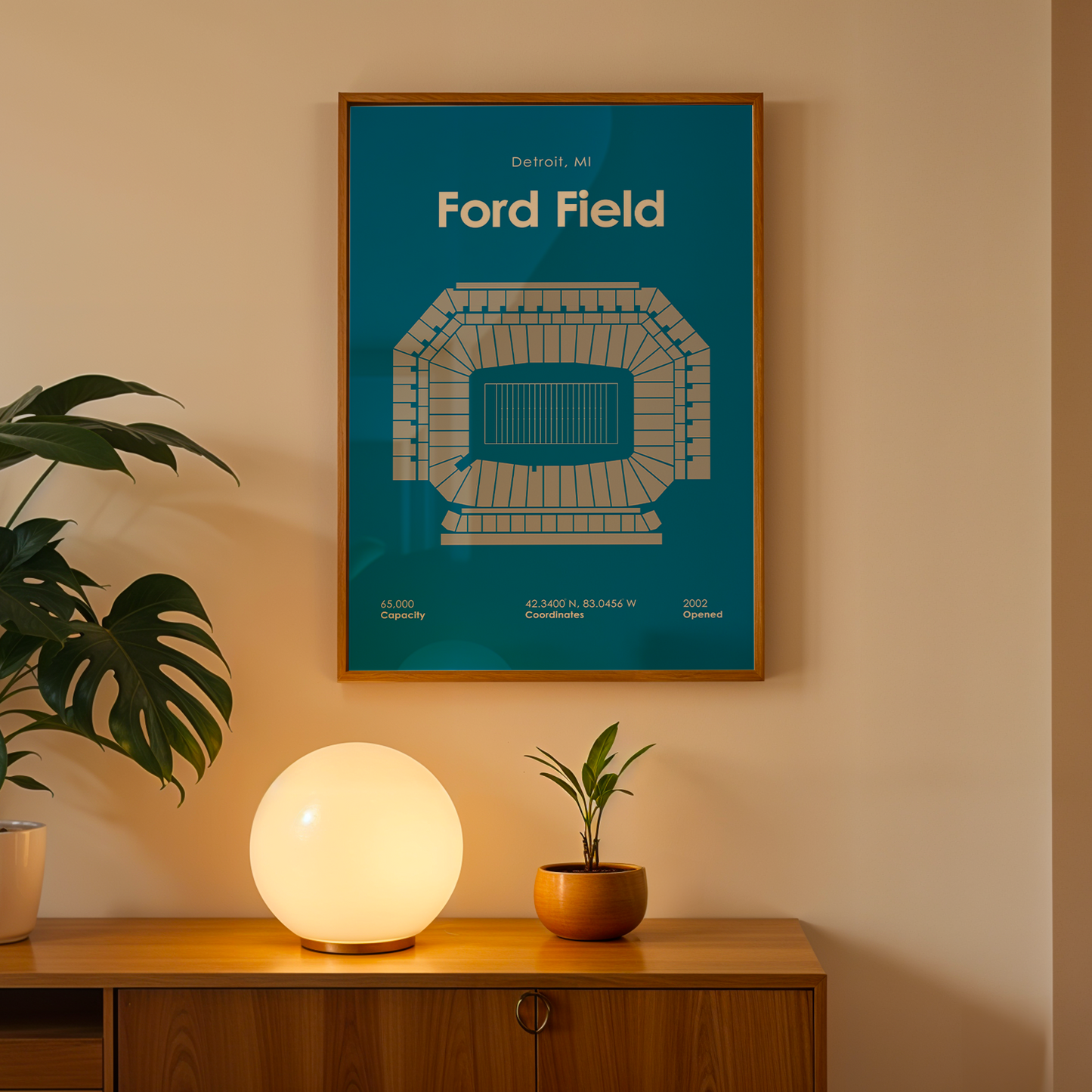 Framed poster of Ford Field on a wall above a wooden cabinet with decorative items.