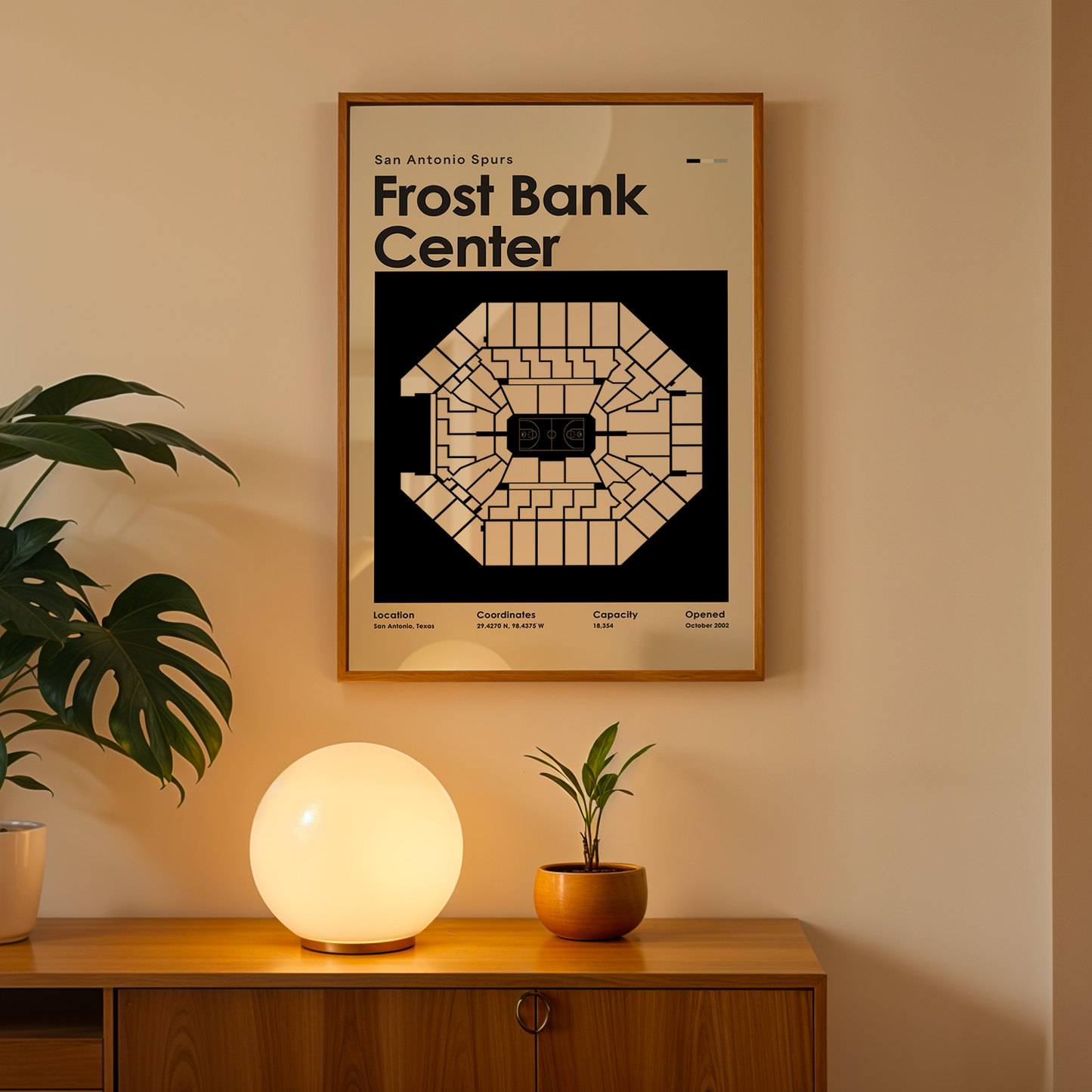 Framed poster of Frost Bank Center on a wall above a wooden cabinet with decorative items.
