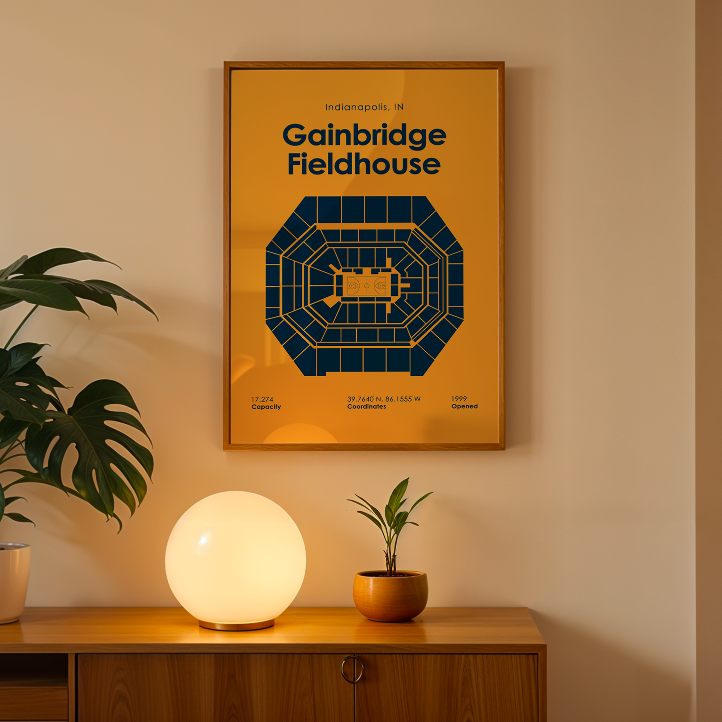 Framed poster of Gainbridge Fieldhouse on a wall above a wooden cabinet with decorative items.